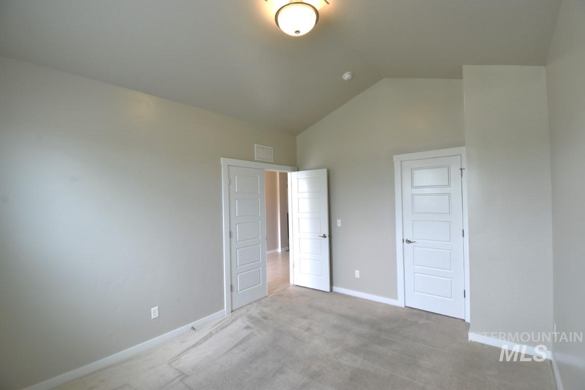 Unfurnished bedroom with lofted ceiling and light colored carpet