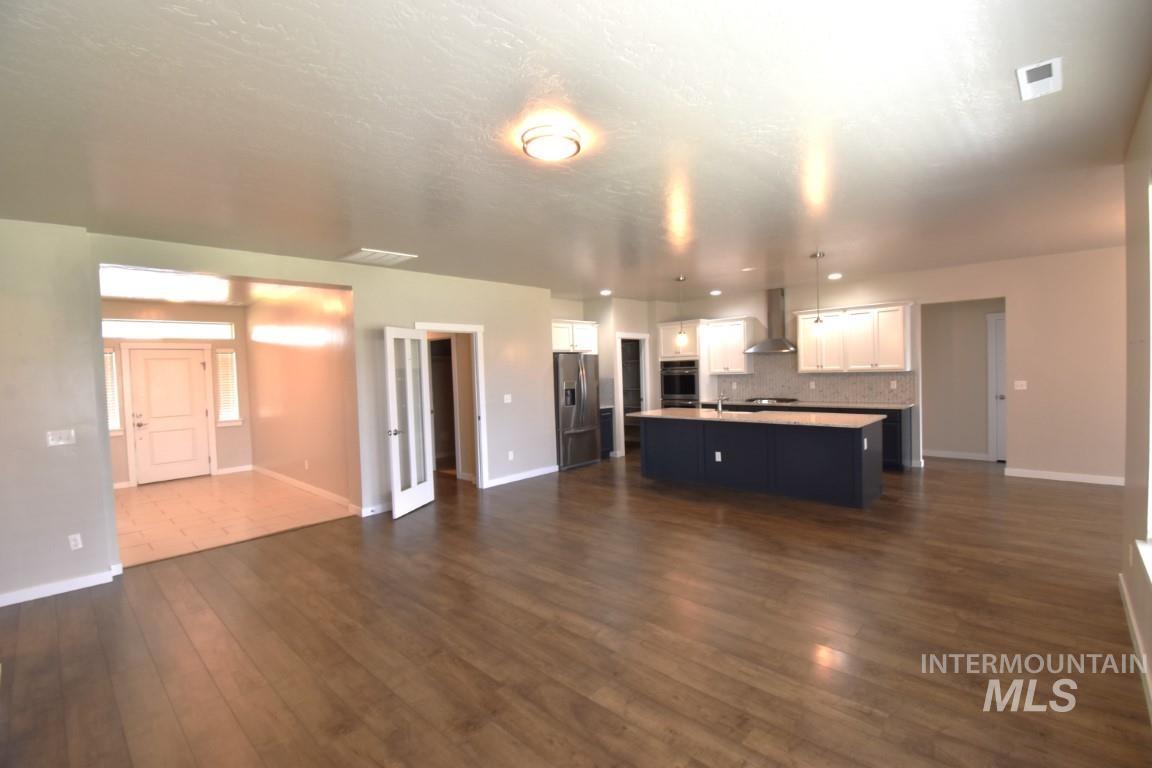 Unfurnished living room with dark wood-style flooring and baseboards