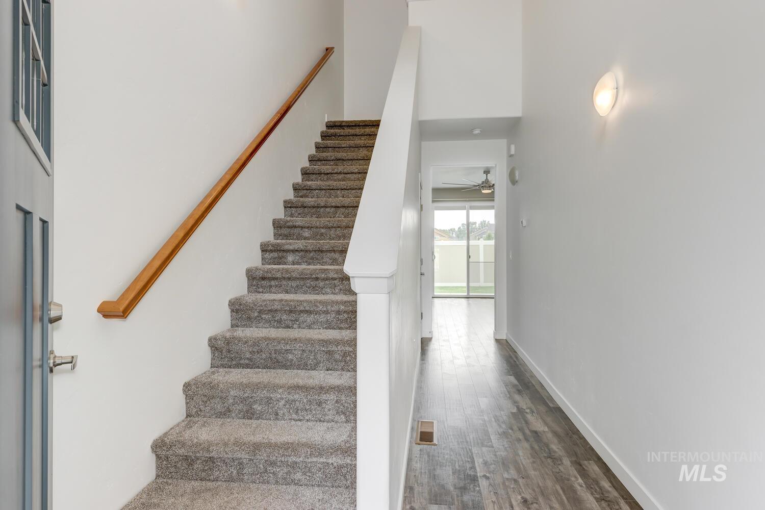 Stairway featuring wood finished floors, a ceiling fan, and a high ceiling