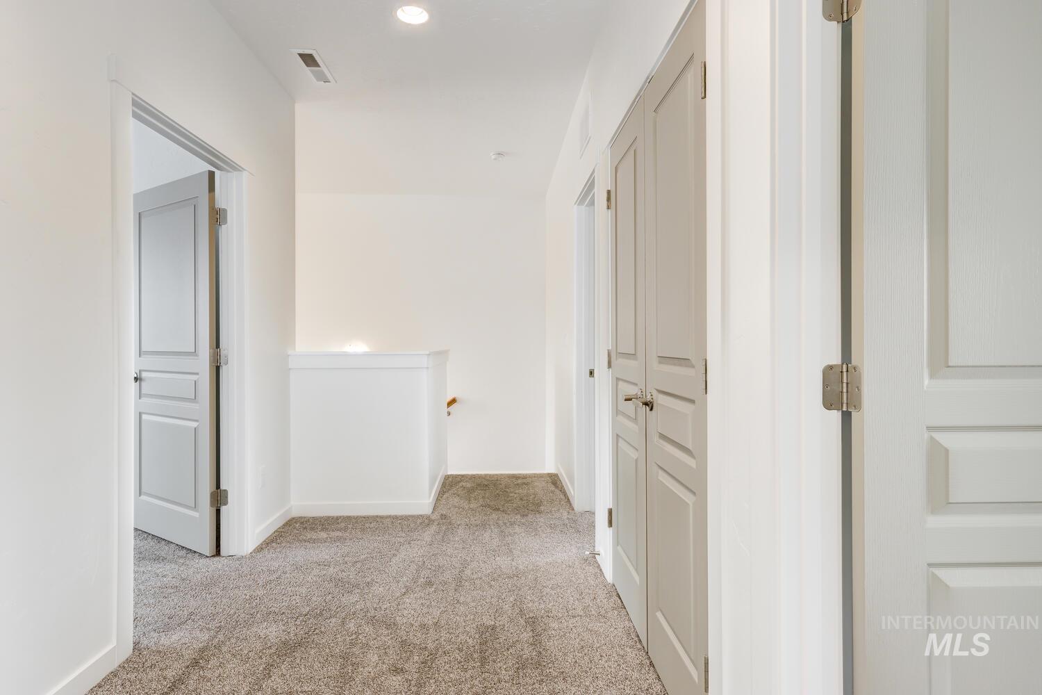 Hall with light colored carpet and an upstairs landing