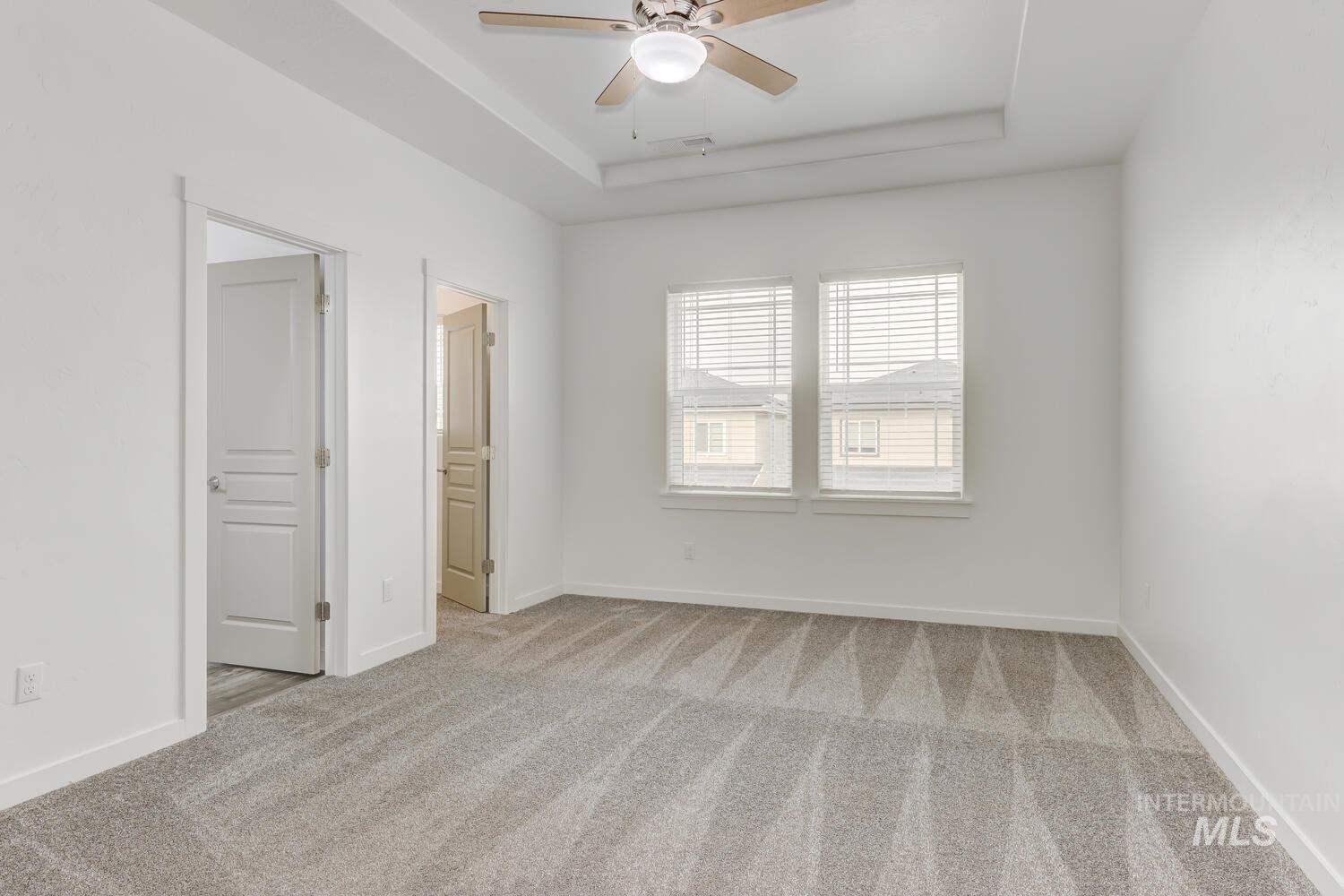 Unfurnished bedroom featuring carpet floors, a raised ceiling, and ensuite bathroom