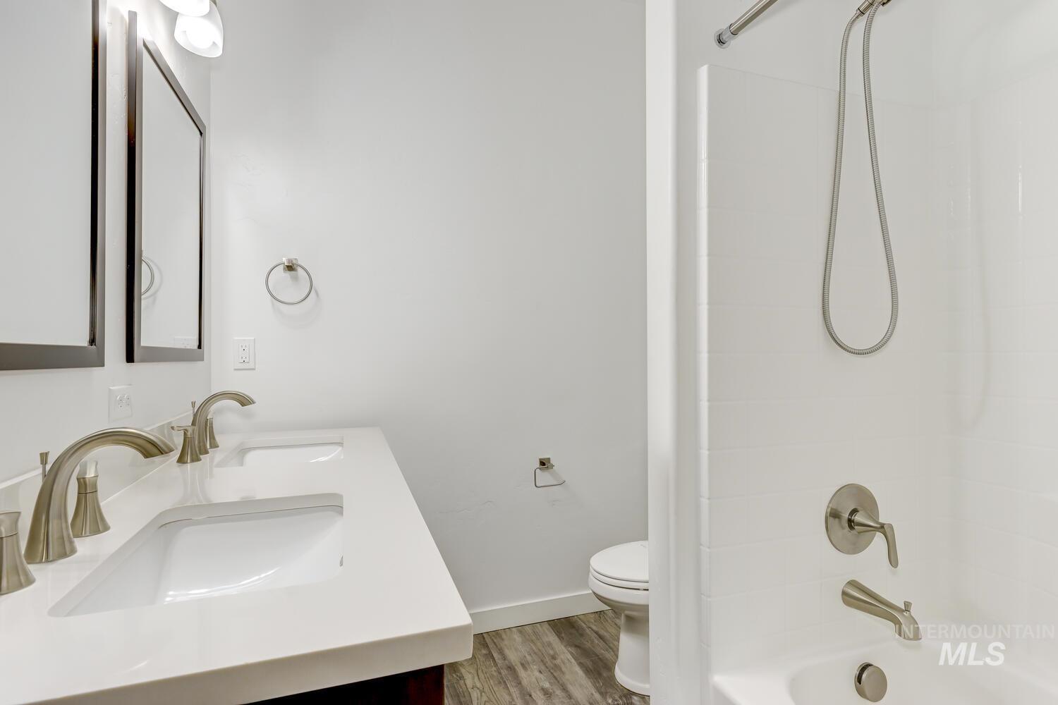 Bathroom featuring double vanity, wood finished floors, and bathtub / shower combination