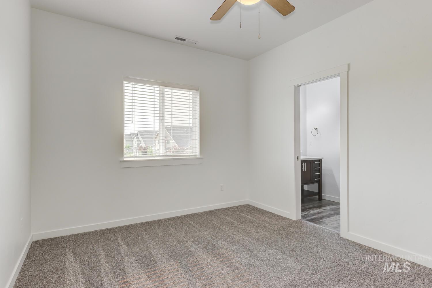 Unfurnished bedroom with carpet flooring, ensuite bathroom, and ceiling fan