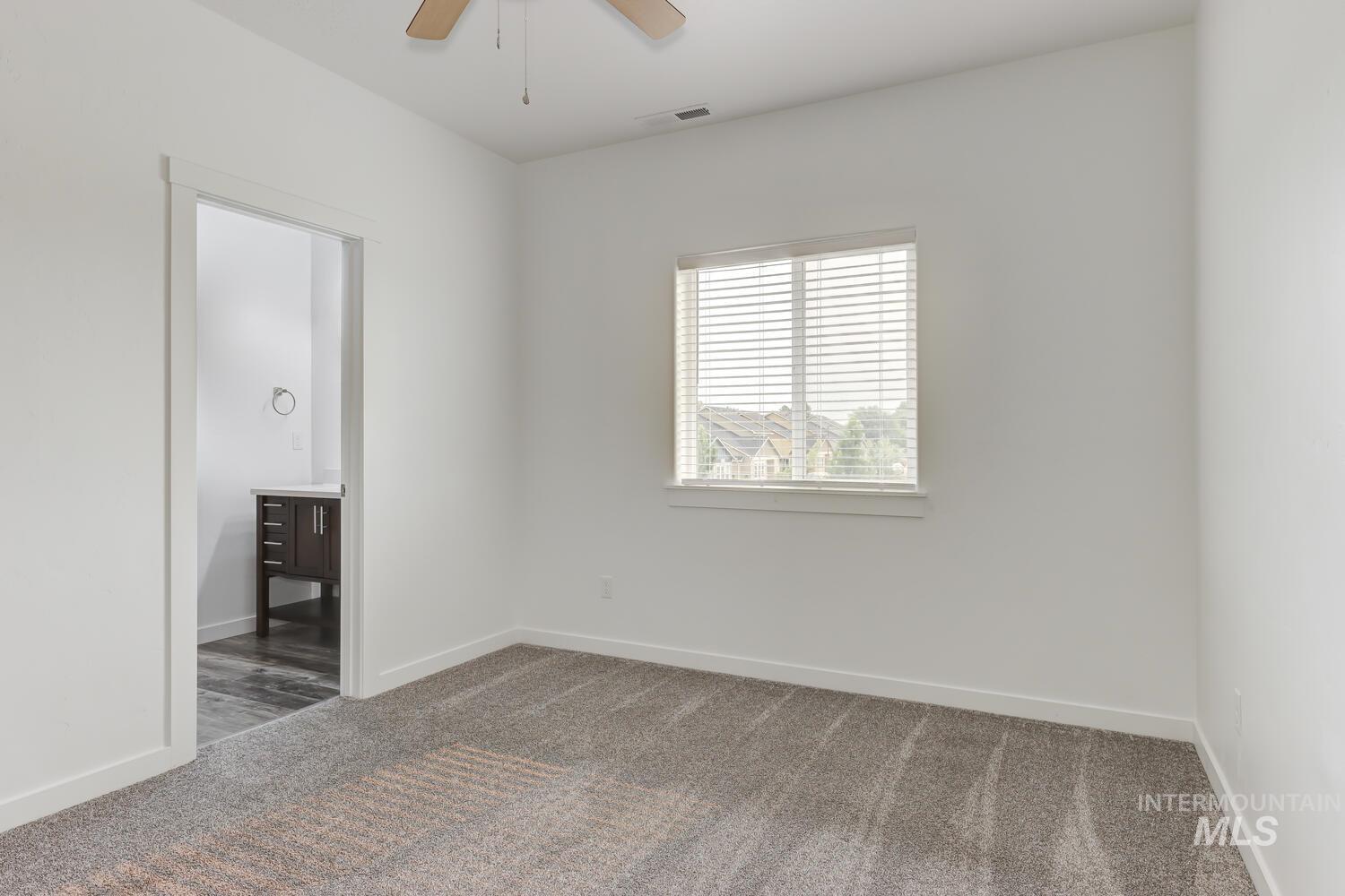 Unfurnished bedroom with carpet flooring, ensuite bath, and ceiling fan