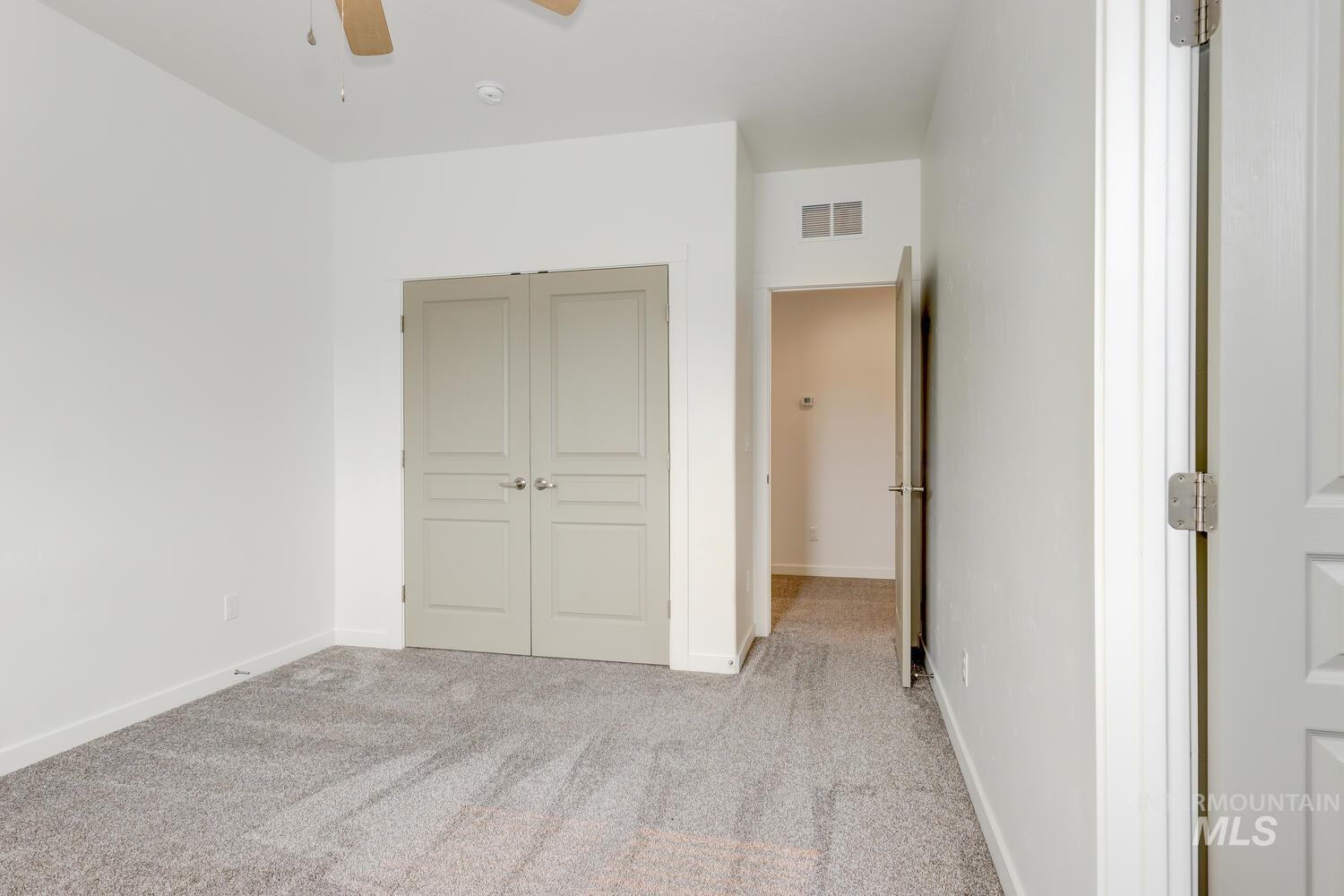 Unfurnished bedroom featuring carpet, a closet, and a ceiling fan