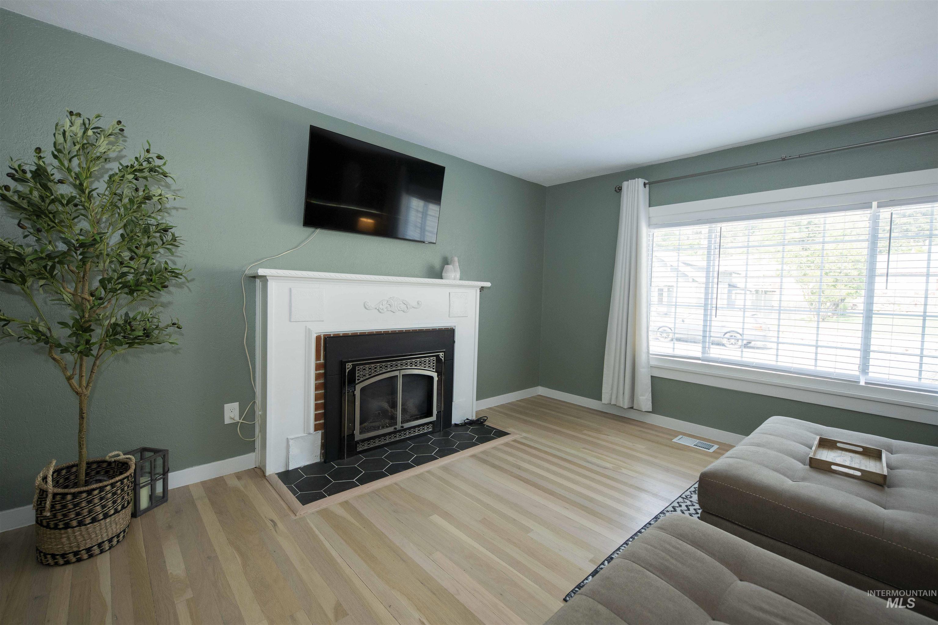 Living room with wood finished floors and a glass covered fireplace