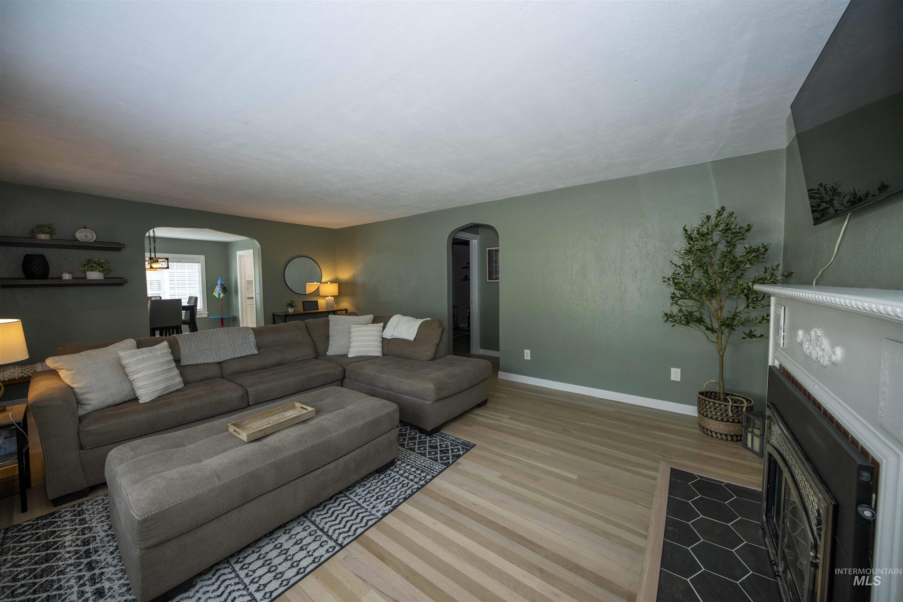 Living area featuring arched walkways, light wood-type flooring, and a fireplace with flush hearth