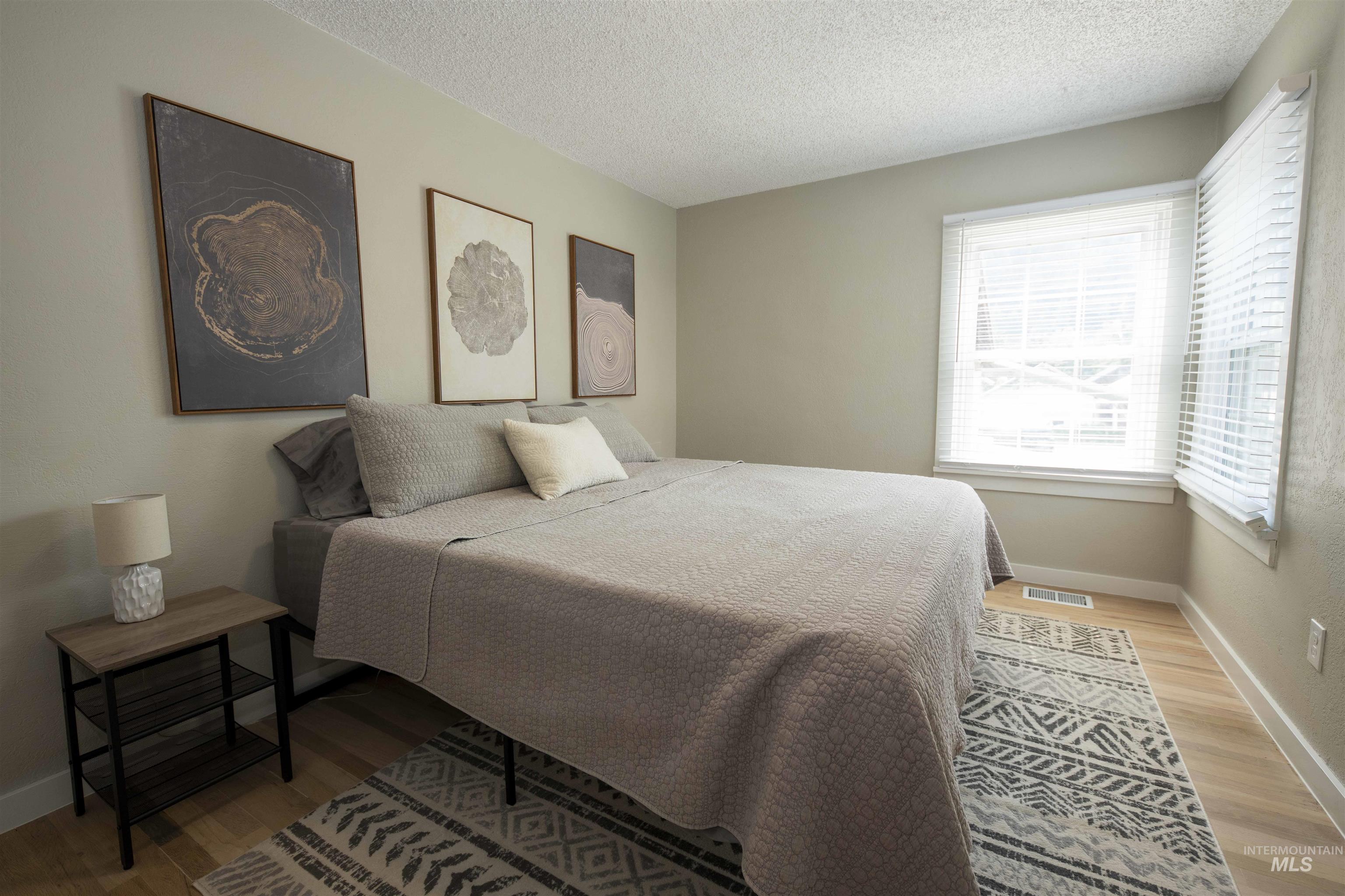 Bedroom with a textured ceiling and light wood-style flooring