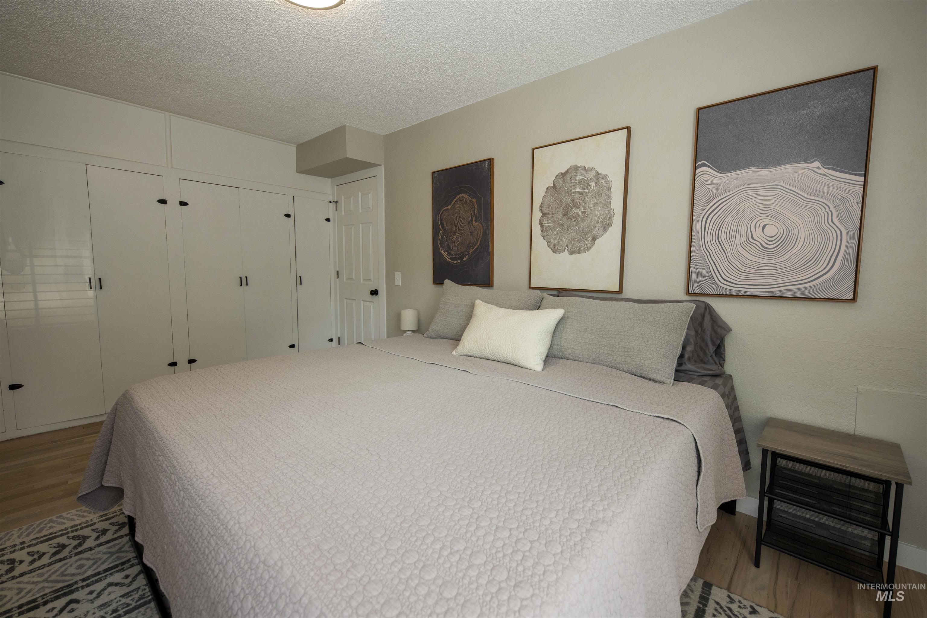 Bedroom with wood finished floors, a textured ceiling, and a closet