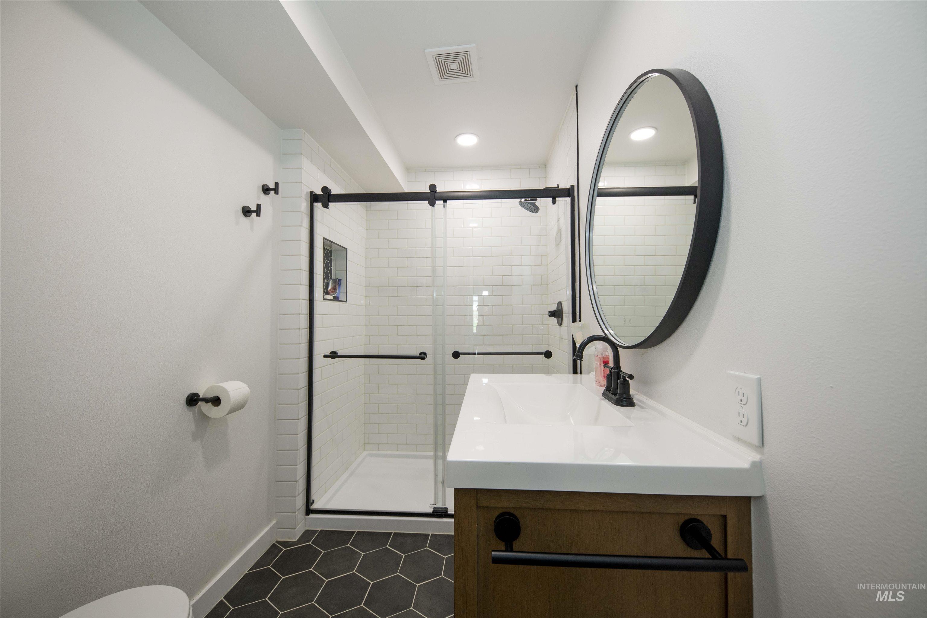 Bathroom featuring vanity, a stall shower, recessed lighting, and tile patterned flooring