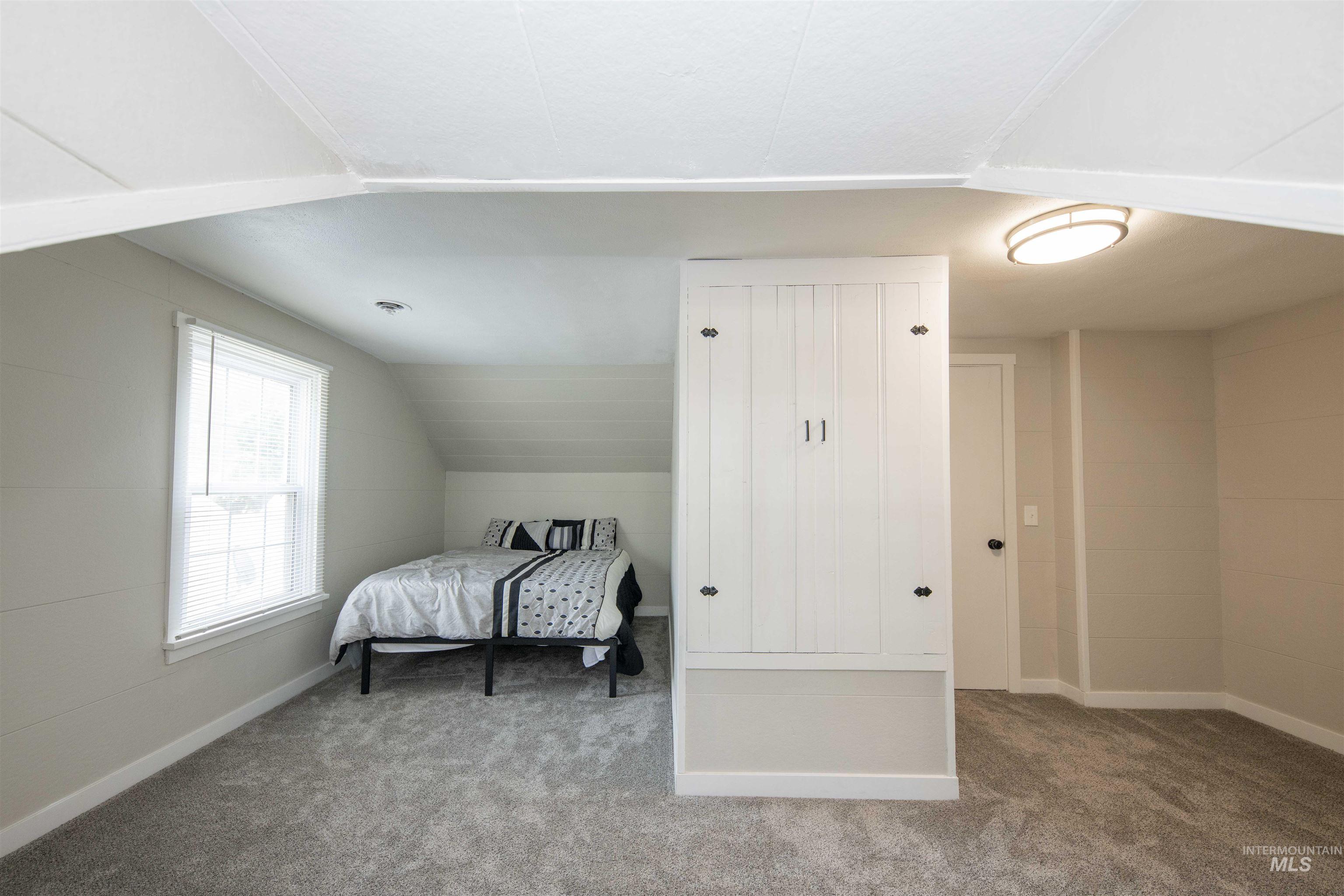 Carpeted bedroom with baseboards and vaulted ceiling