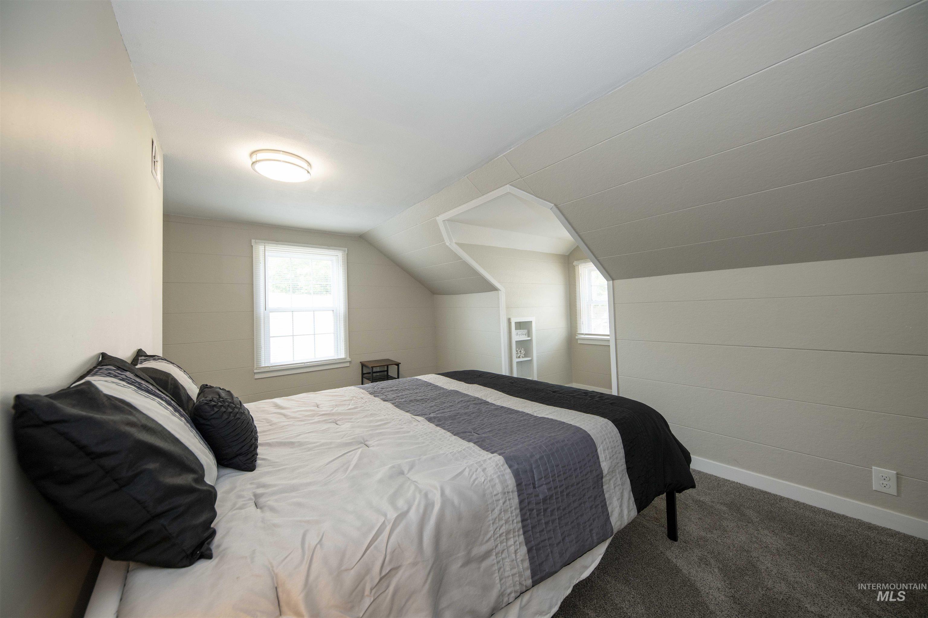 Carpeted bedroom featuring baseboards and vaulted ceiling