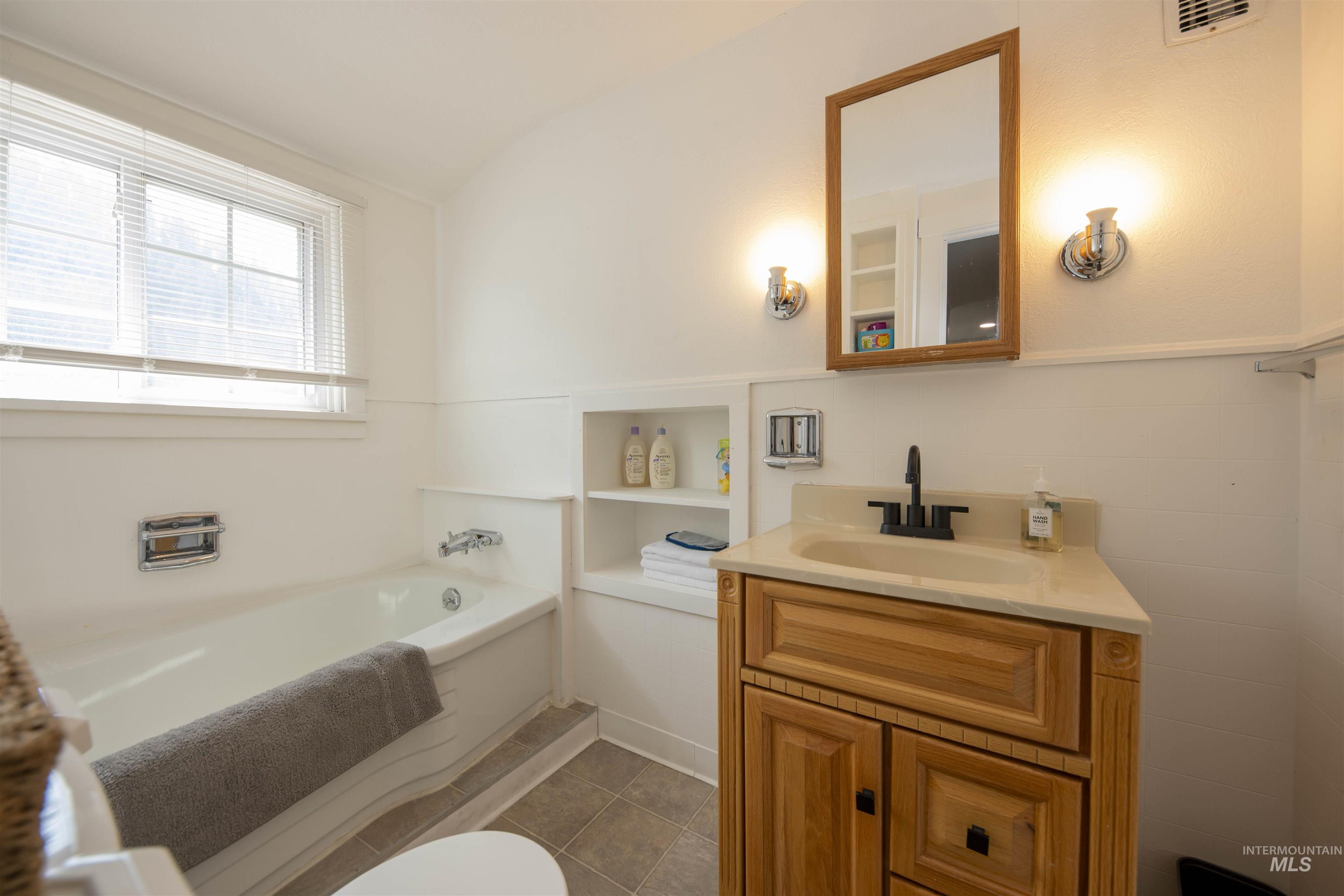 Bathroom featuring a garden tub, vanity, and vaulted ceiling