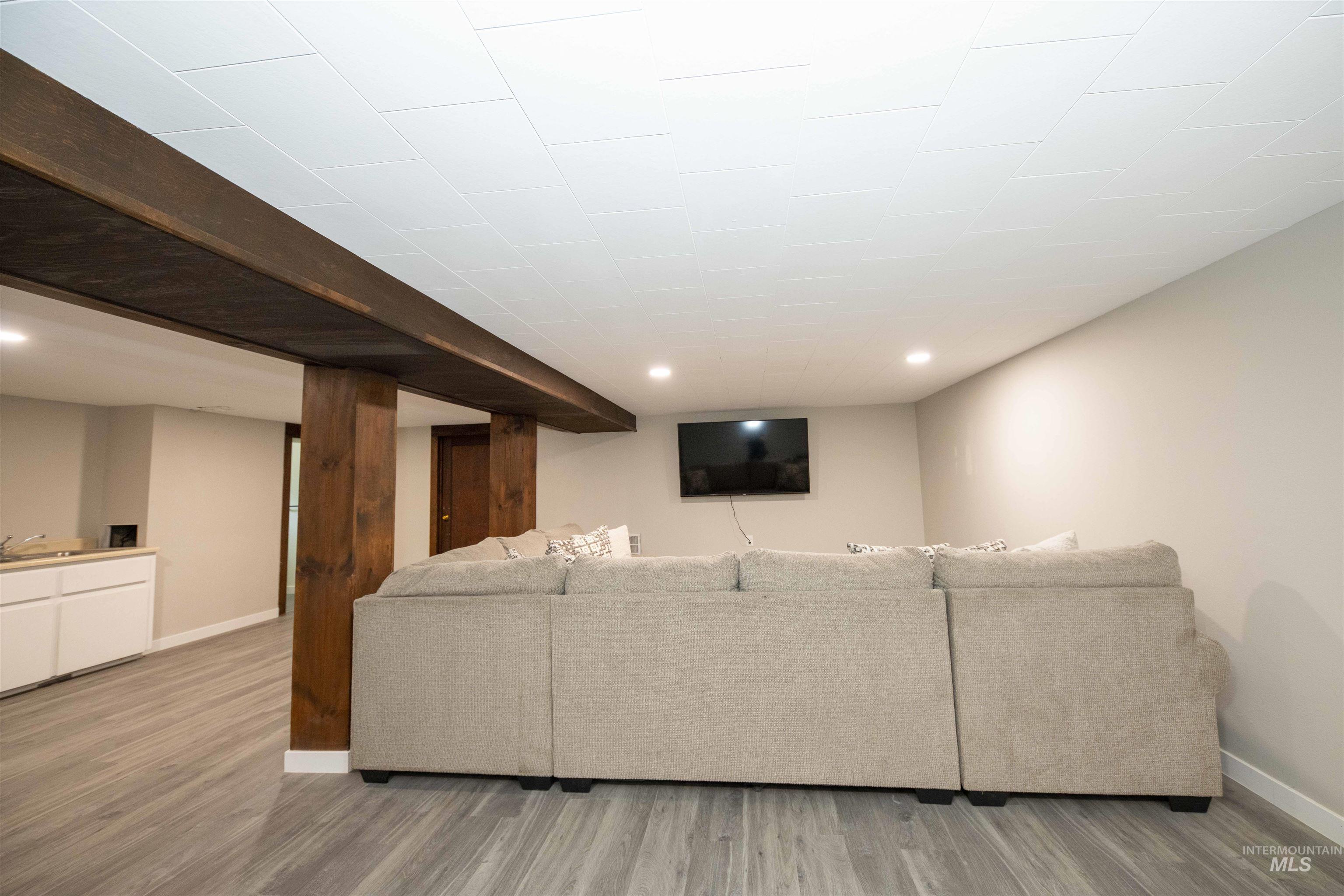 Living room in basement of main house with light wood-style flooring and recessed lighting