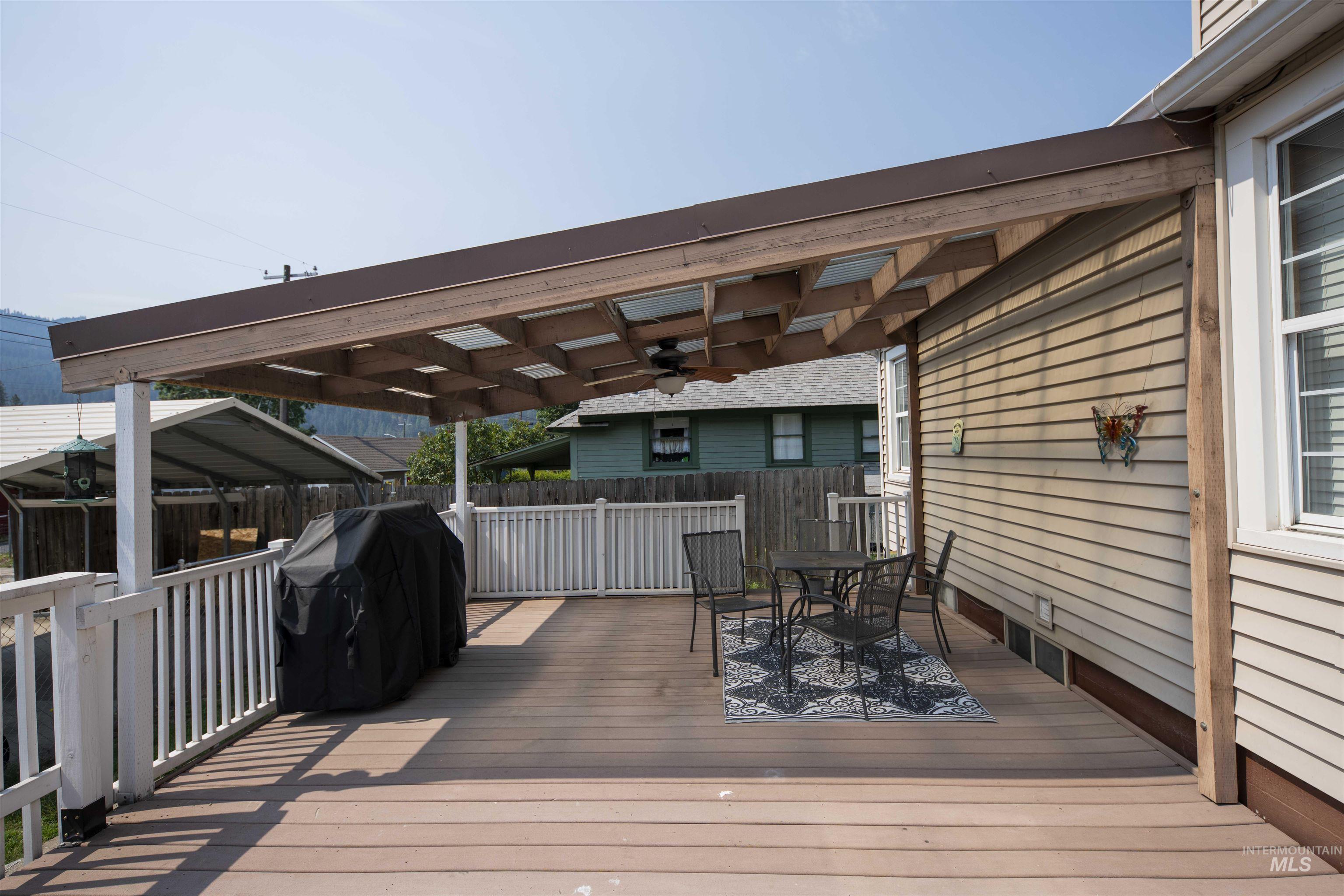Deck with outdoor dining space, area for grilling, and a ceiling fan