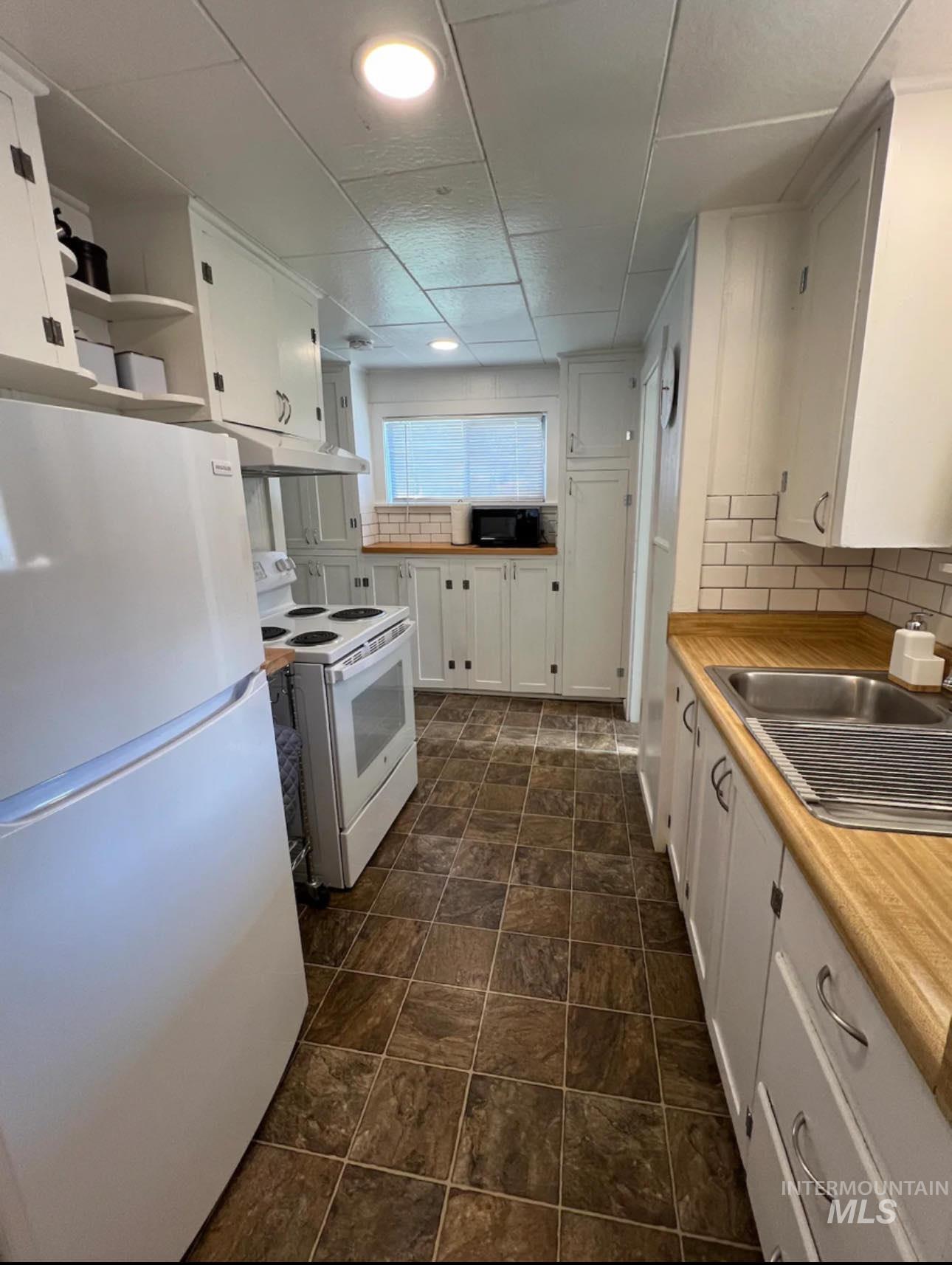 2nd home / AirBNB - Kitchen with white appliances, white cabinetry, tasteful backsplash, and light countertops