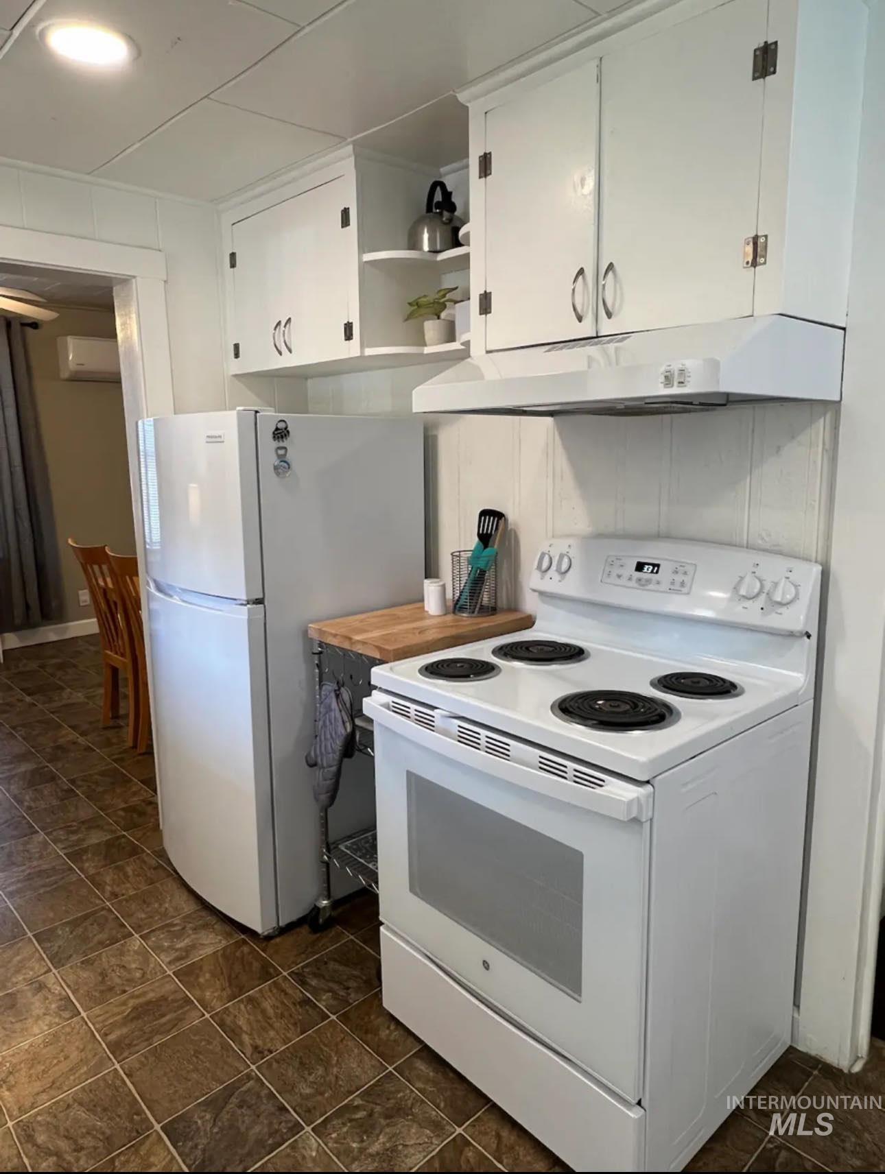 2nd home / AirBNB - Kitchen featuring white electric range, under cabinet range hood, open shelves, white cabinets, and a wall mounted AC