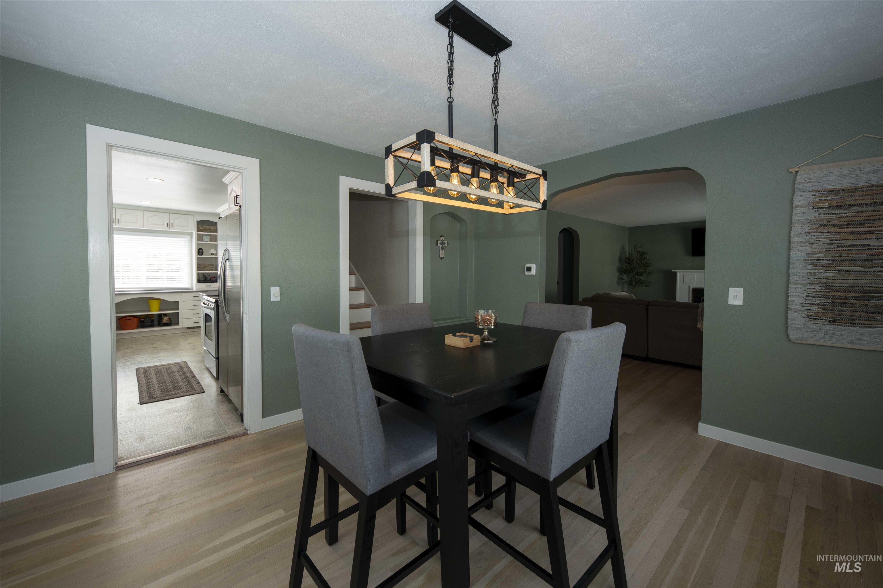 Dining space featuring wood finished floors, arched walkways, and stairs