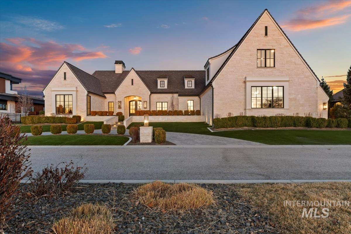 View of front of home with a chimney, a front yard, and stone siding