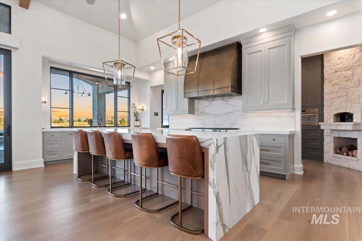 Kitchen with gray cabinets, a center island, premium range hood, backsplash, and light wood finished floors