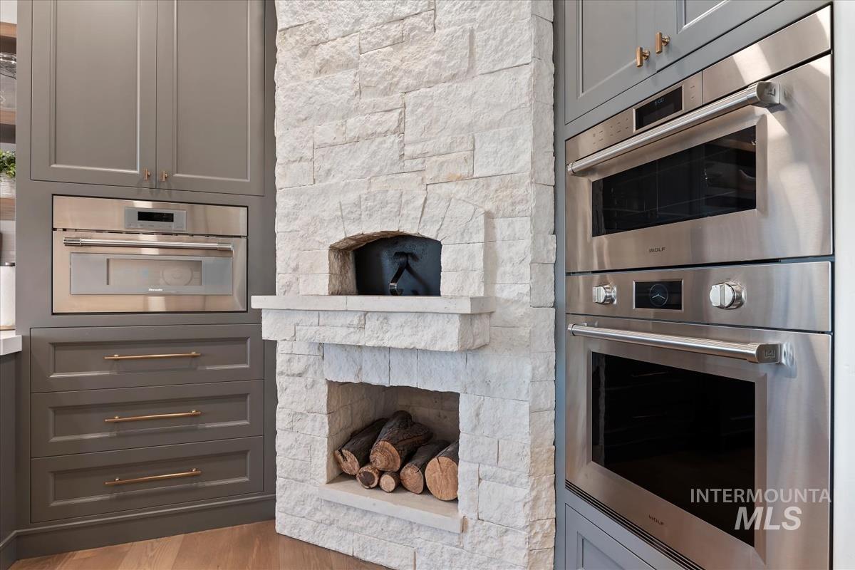 Kitchen with double oven, gray cabinetry, and wood finished floors