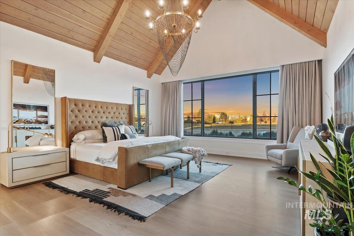 Bedroom with high vaulted ceiling, a wood ceiling with exposed beams, wood finished floors, and a chandelier