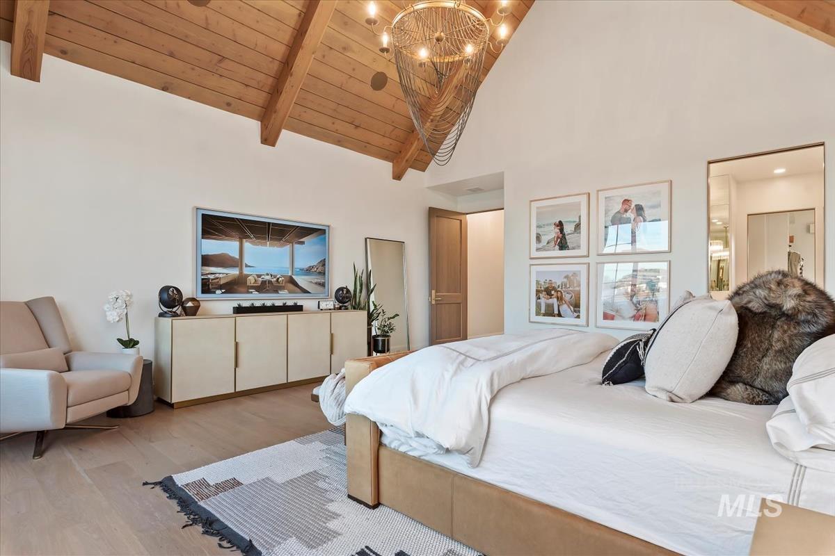 Bedroom featuring high vaulted ceiling, light wood-type flooring, a wooden ceiling with exposed beams, and a chandelier