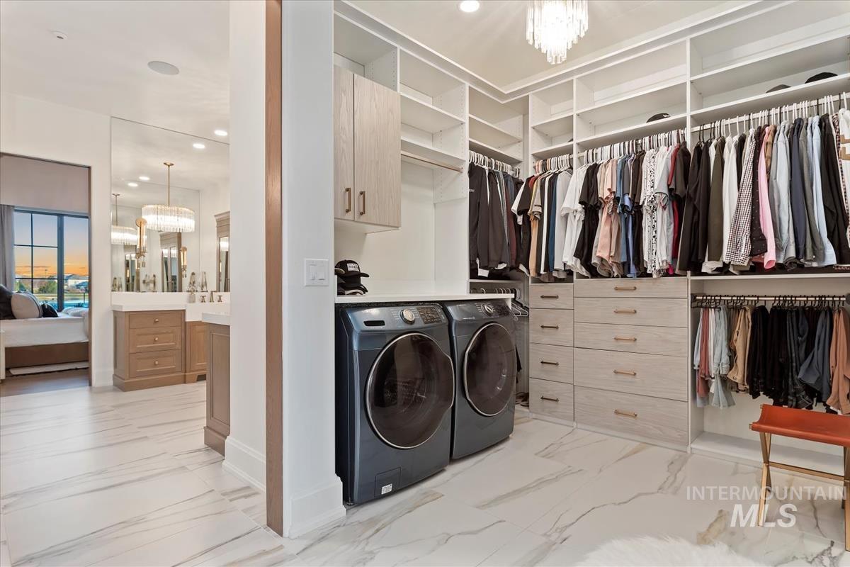 Washroom featuring a chandelier, washing machine and dryer, cabinet space, light marble finish floors, and recessed lighting