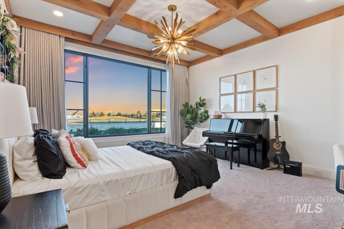 Bedroom featuring carpet floors, multiple windows, coffered ceiling, beam ceiling, and a chandelier