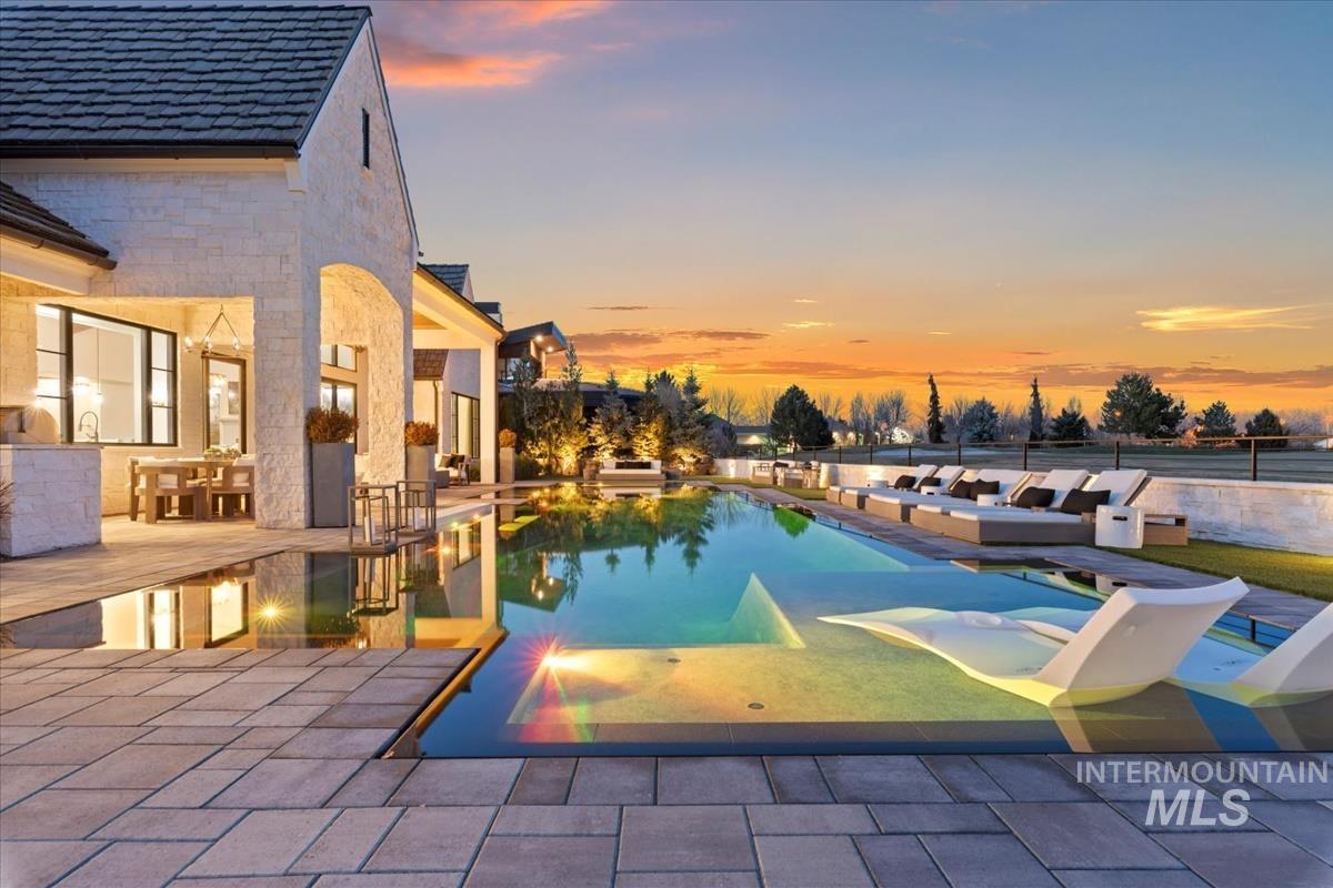 Pool at dusk featuring a patio