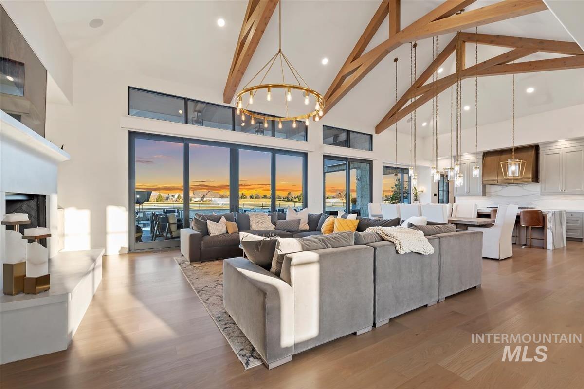 Living area featuring a chandelier, high vaulted ceiling, beamed ceiling, wood finished floors, and recessed lighting