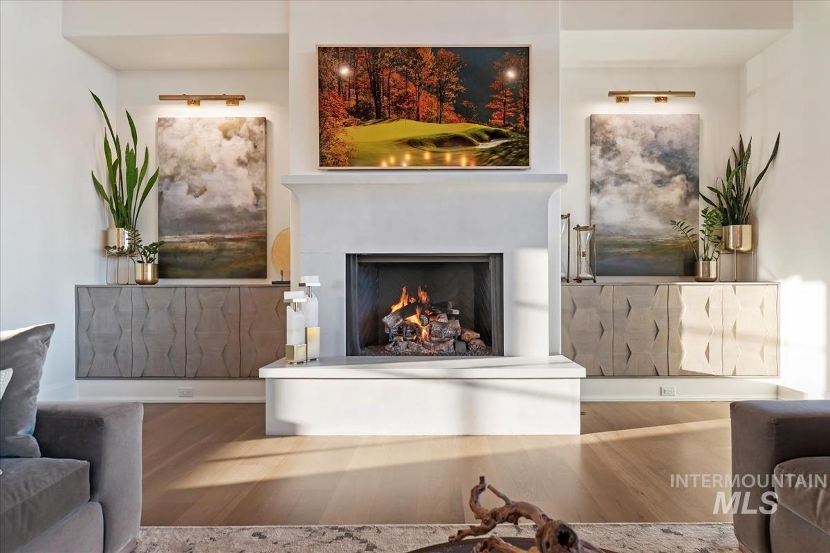 Living room with a warm lit fireplace and wood finished floors