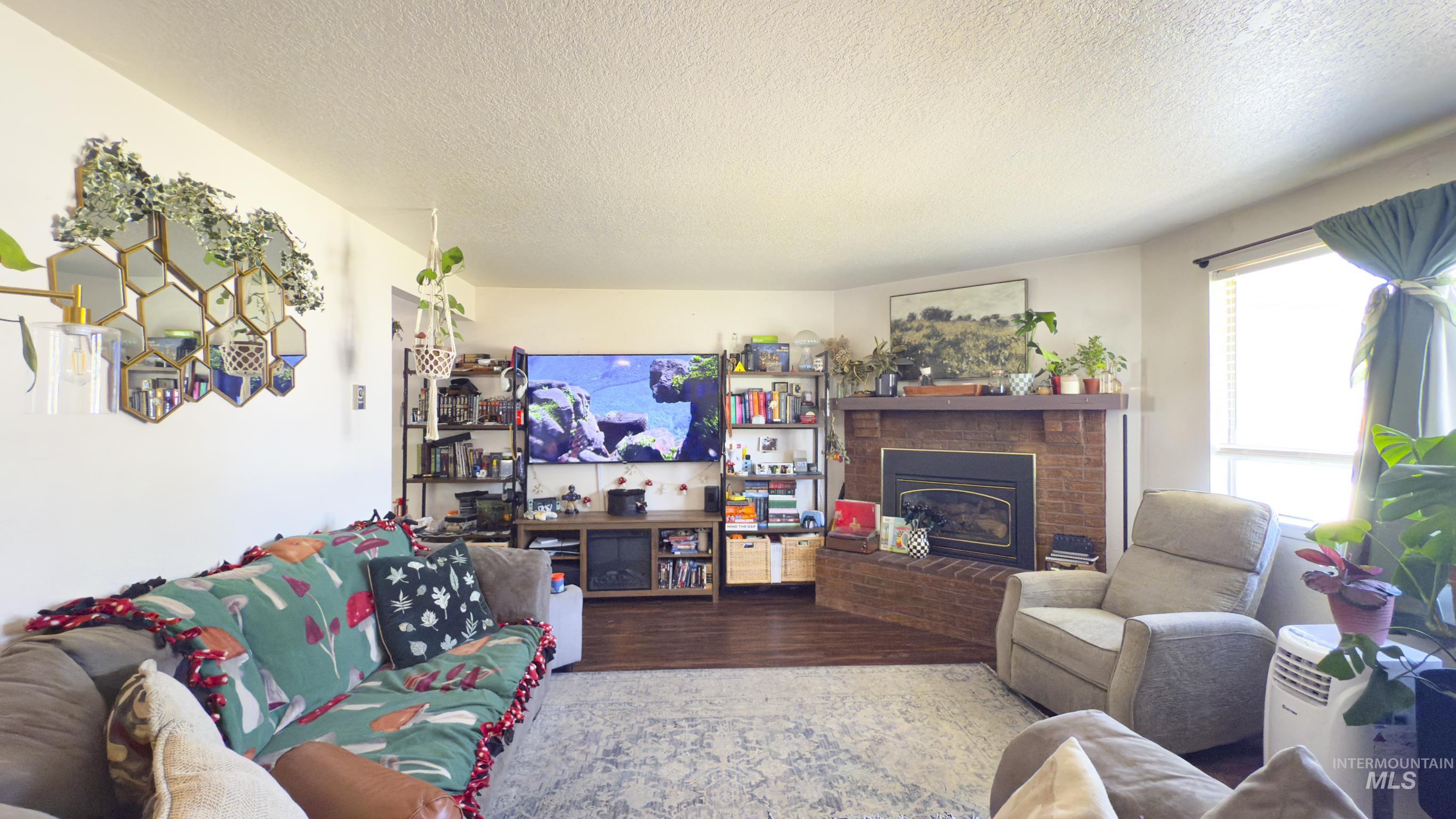 Living area featuring a textured ceiling, wood finished floors, and a fireplace