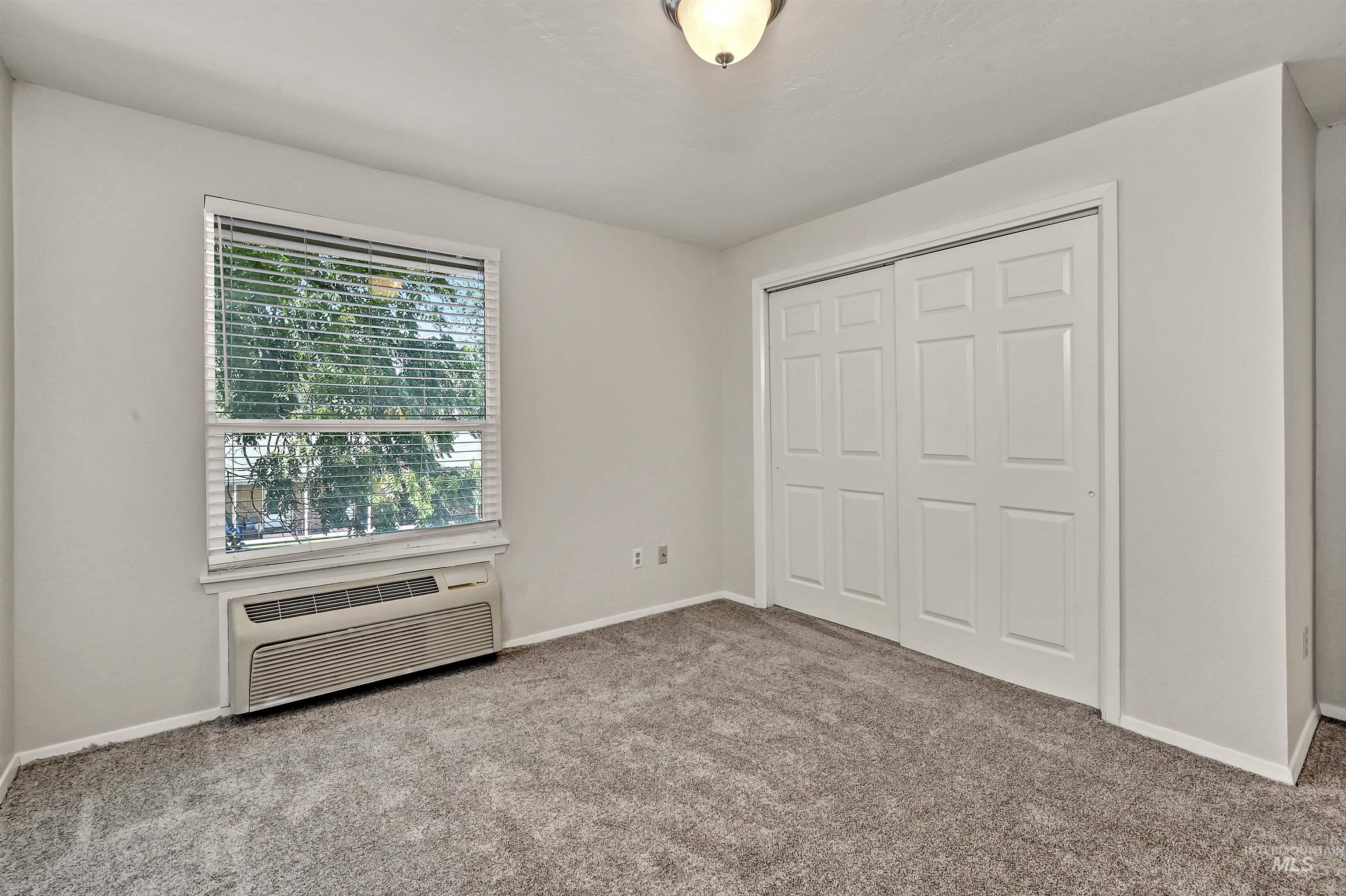 Unit A: Bedroom 3 with carpet flooring, a closet, and a wall mounted air conditioner
