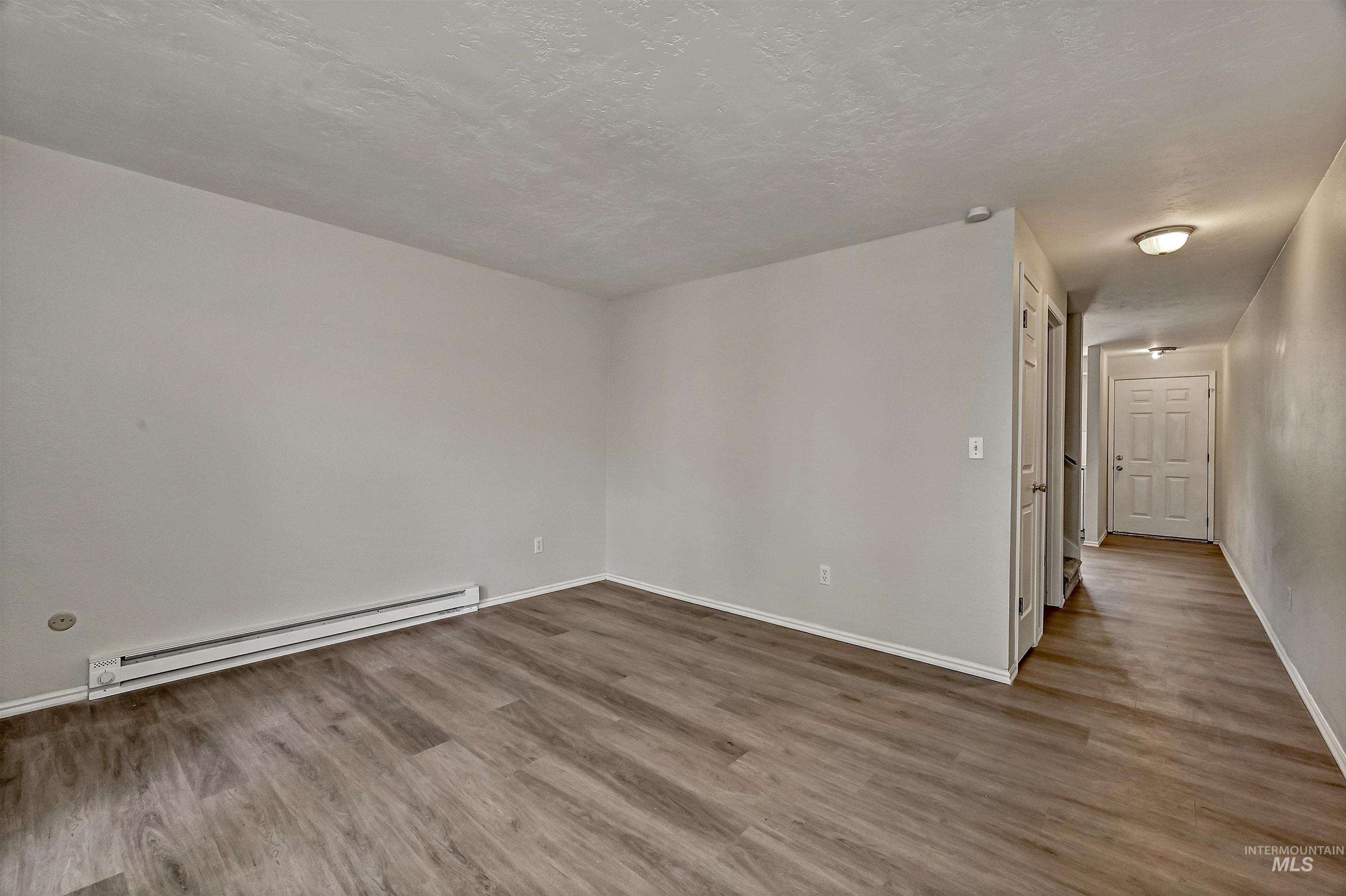 Unit B: Living room with baseboard radiator, LVP flooring, and a textured ceiling
