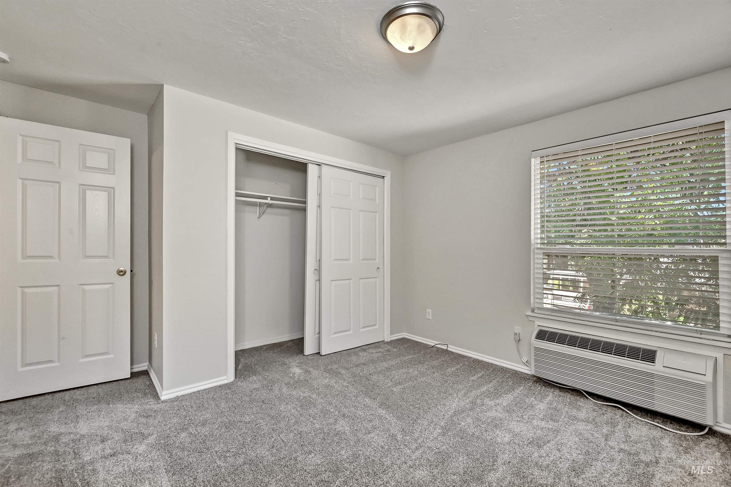 Unit B: Bedroom 1 with carpet, a closet, and a wall mounted AC