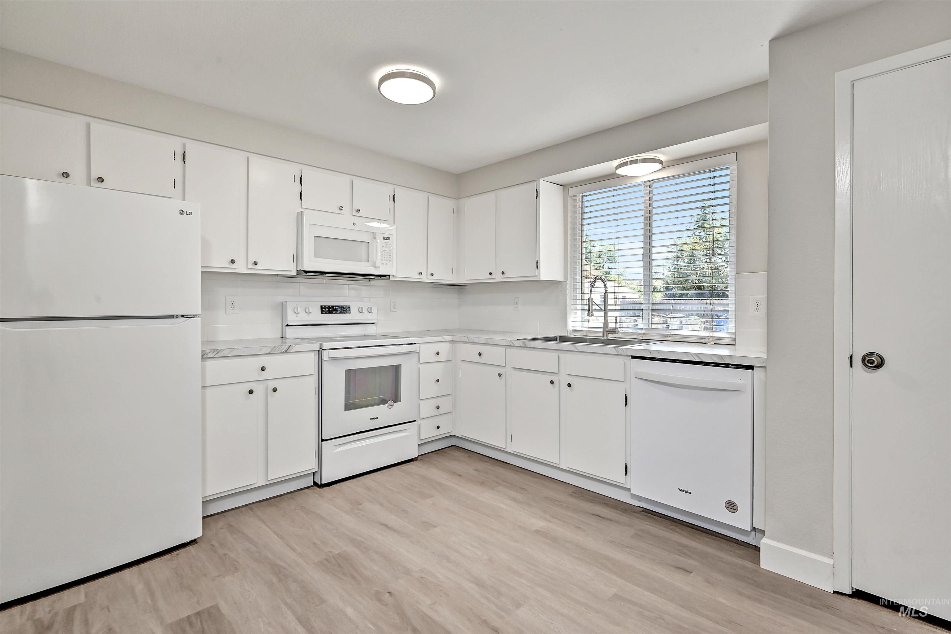 Unit C: Entry and Kitchen featuring white appliances, white cabinetry, light countertops, and LVP flooring