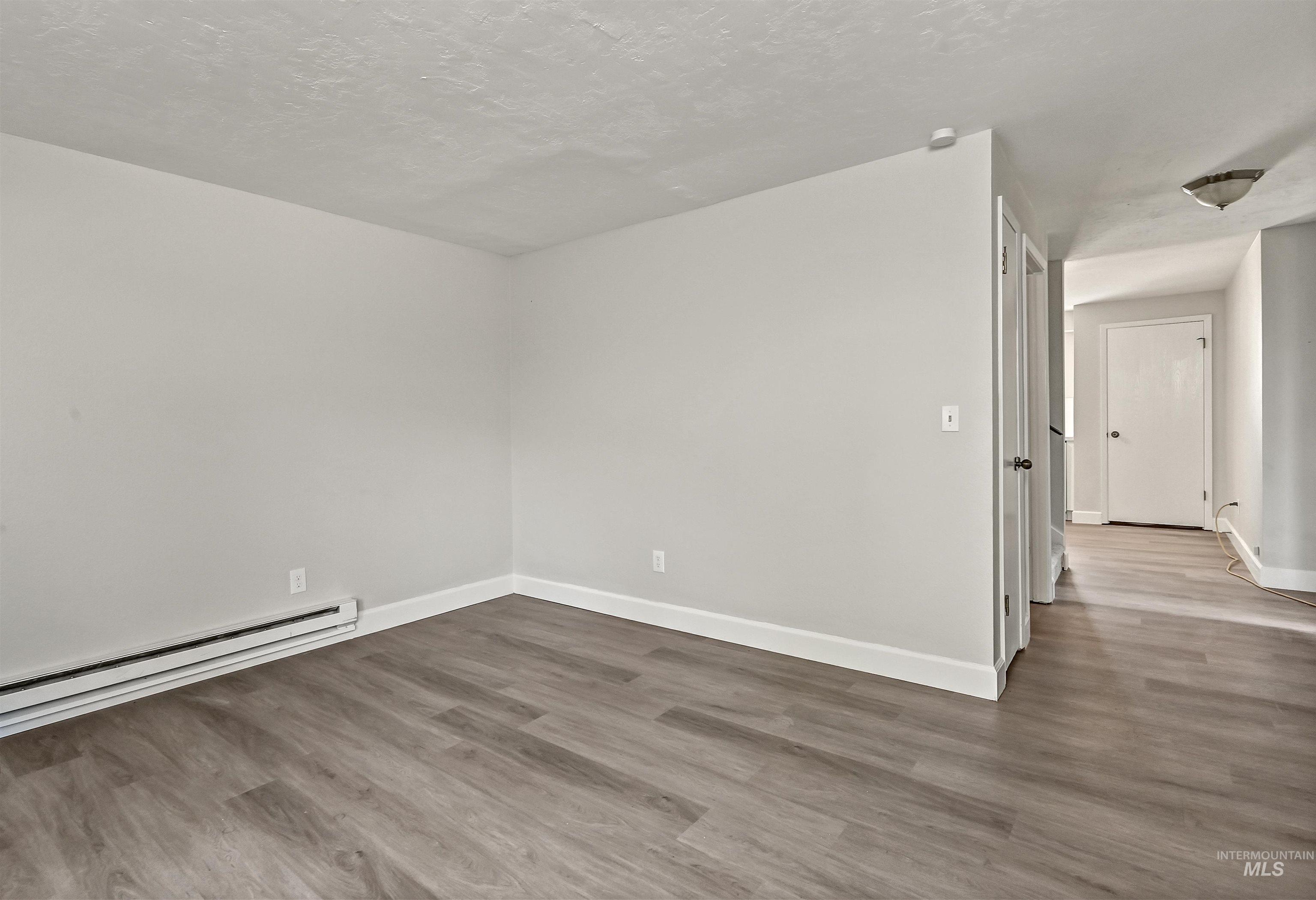 Unit C: Living room featuring wood-type floors, a textured ceiling, and baseboard heating