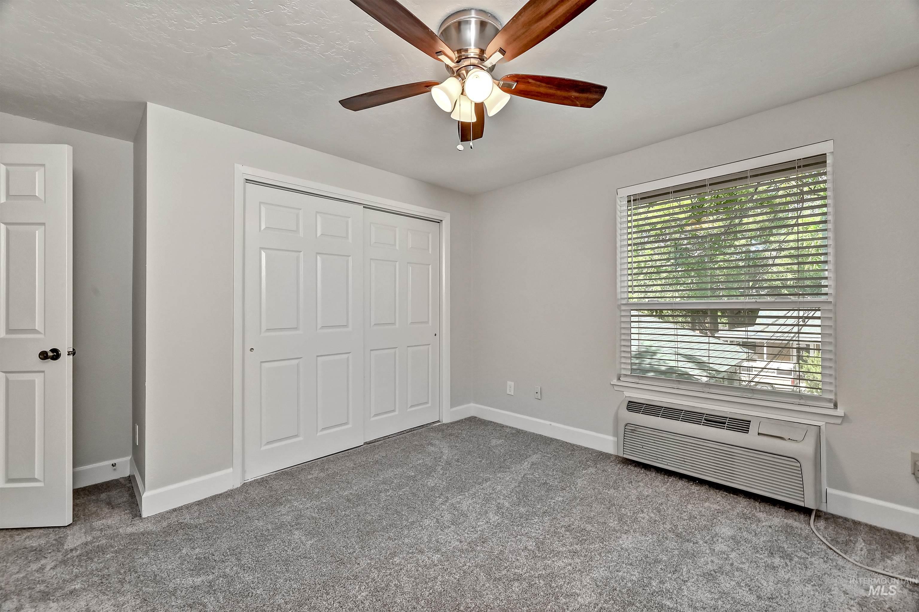 Unit C: Bedroom 2 featuring carpet flooring, a closet, a wall mounted air conditioner, ceiling fan, and a textured ceiling