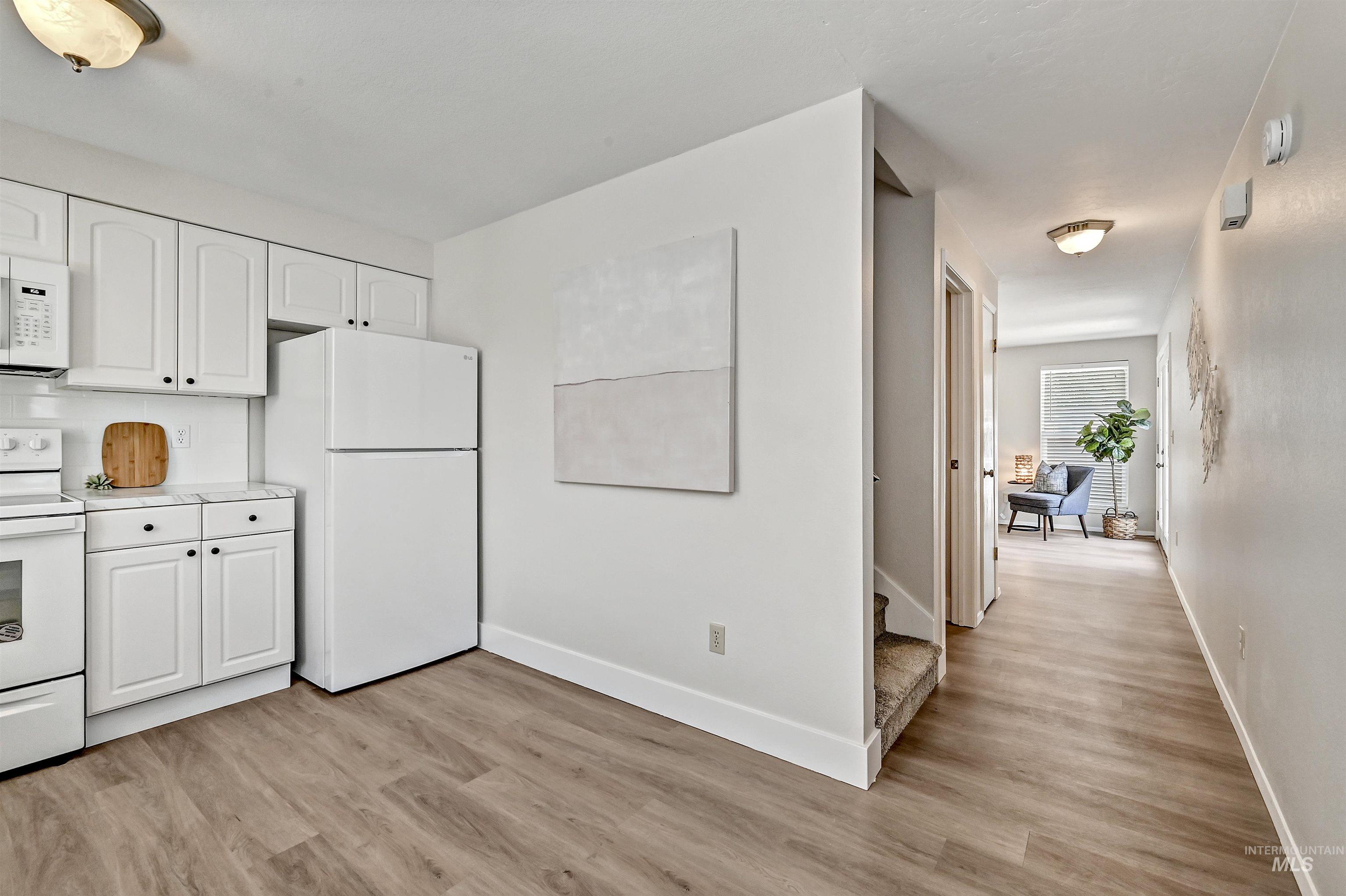 Unit A: Kitchen featuring white appliances, LVP flooring, light countertops, and white cabinetry