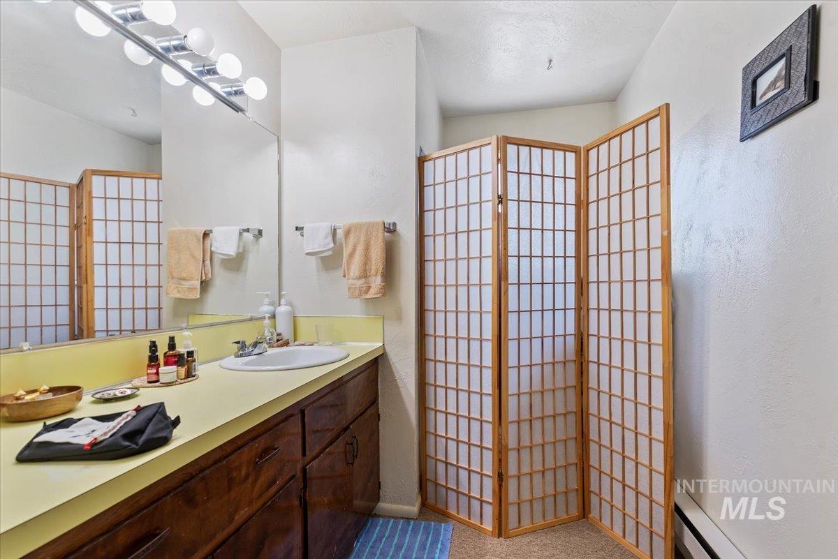 Full bath with vanity and baseboard heating