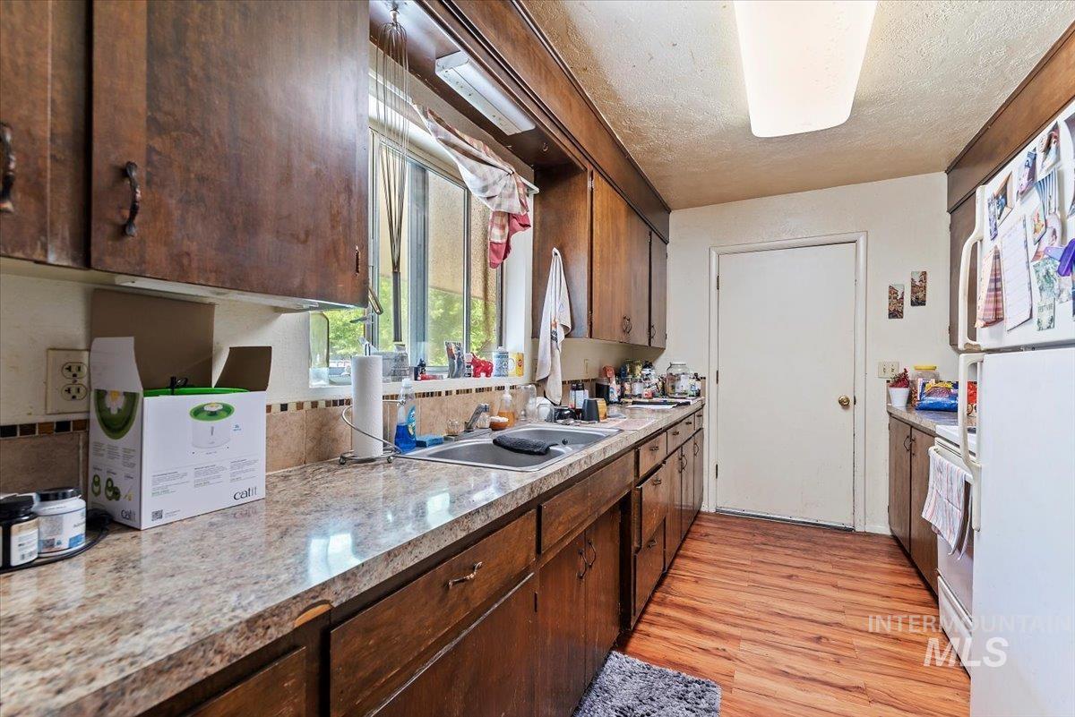 Kitchen featuring freestanding refrigerator, light countertops, light wood-style floors, stove, and a textured ceiling