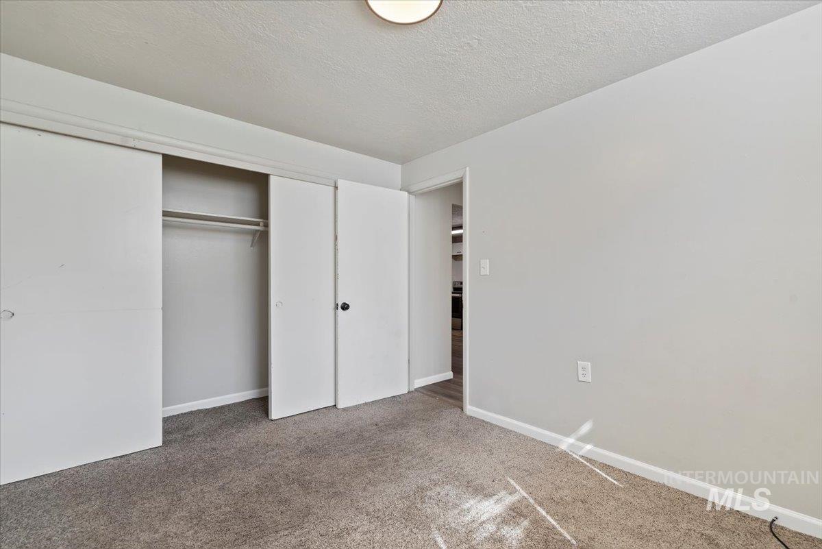 Unfurnished bedroom with a textured ceiling, carpet flooring, and a closet