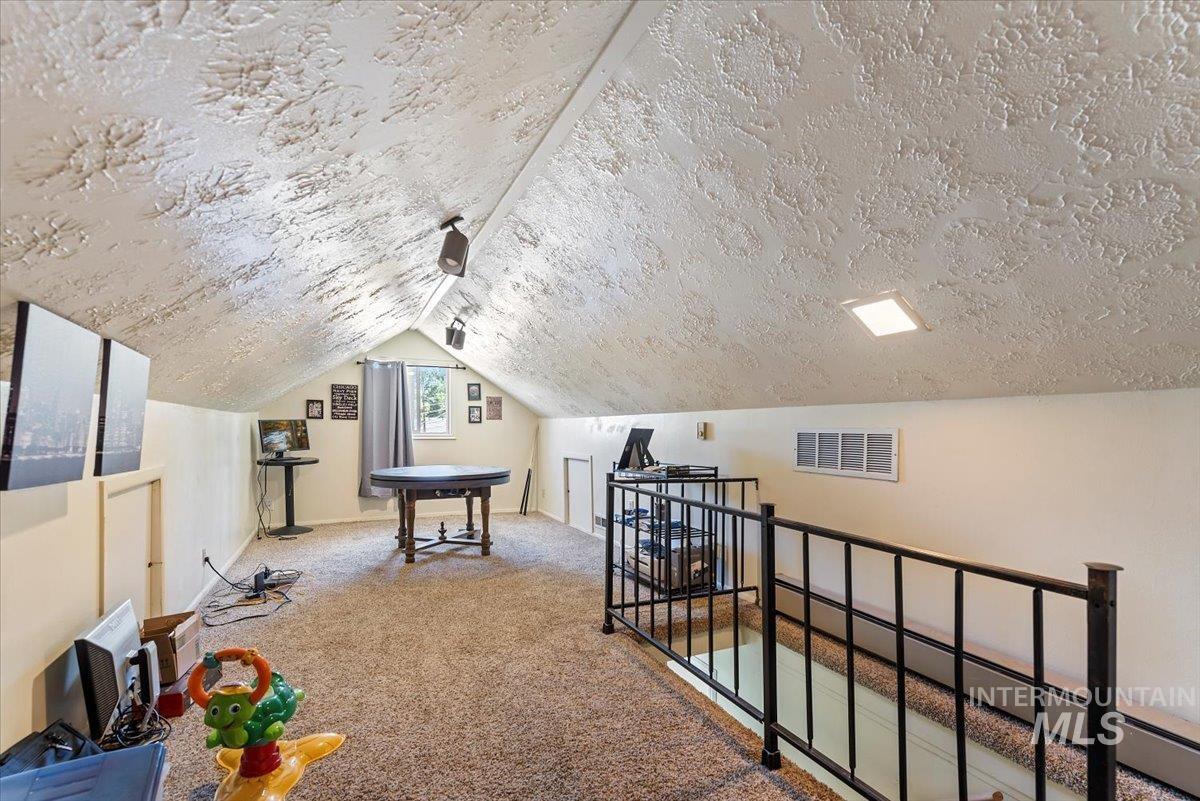 Bonus room with carpet flooring, vaulted ceiling, and a textured ceiling