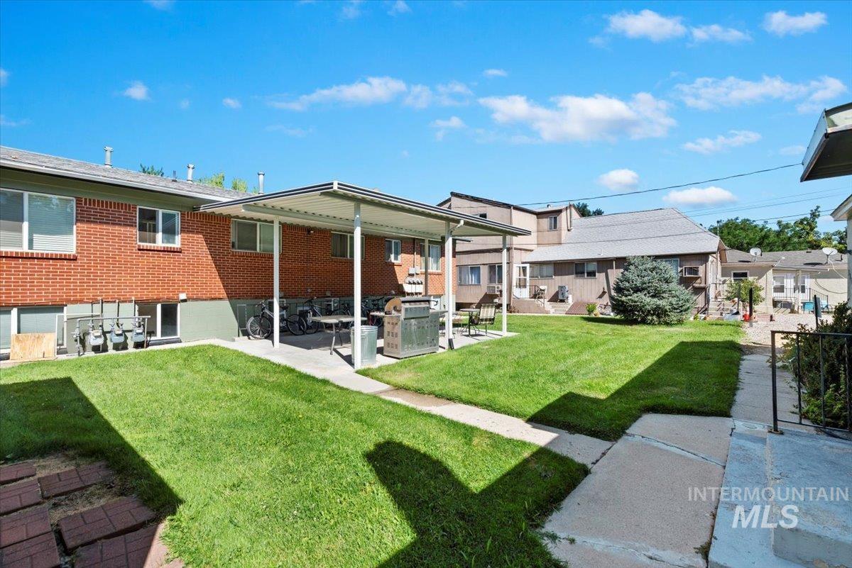 Rear view of house with a lawn, brick siding, and a patio