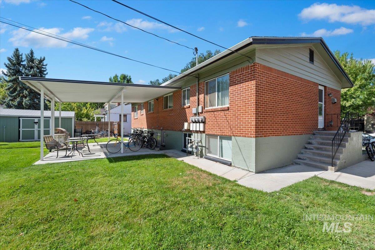 View of side of property featuring a patio area, brick siding, and an outdoor structure