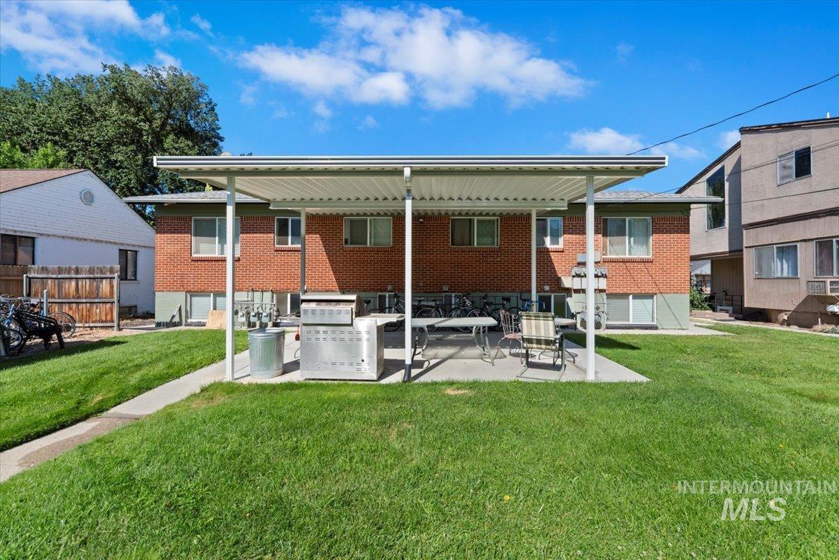 Back of property with a patio area, brick siding, and a yard