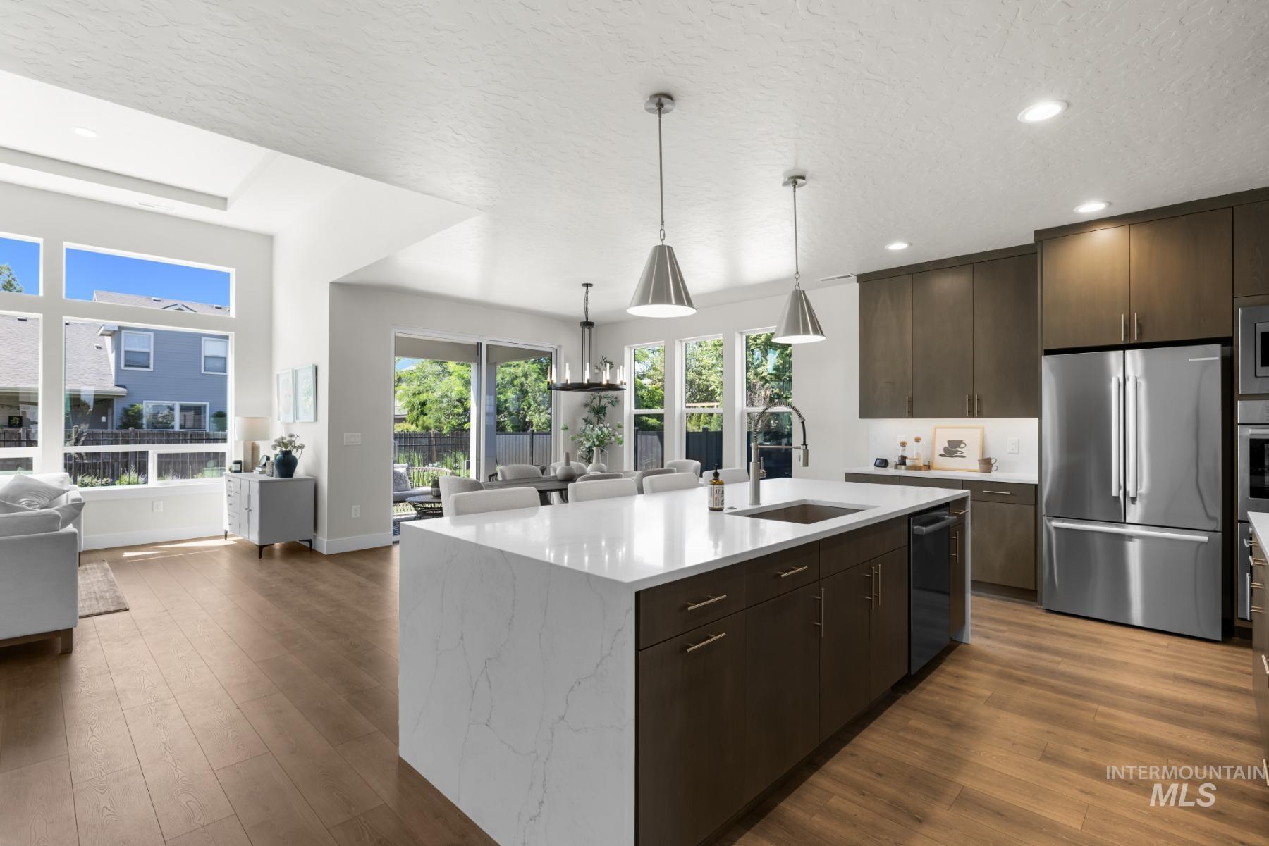 Kitchen with open floor plan, dark wood finished floors, appliances with stainless steel finishes, a textured ceiling, and dark brown cabinetry
