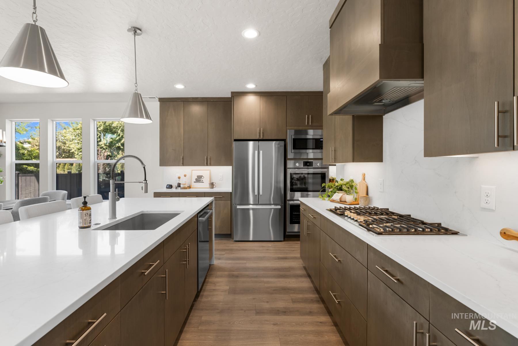 Kitchen featuring recessed lighting, light countertops, premium range hood, stainless steel appliances, and dark wood finished floors