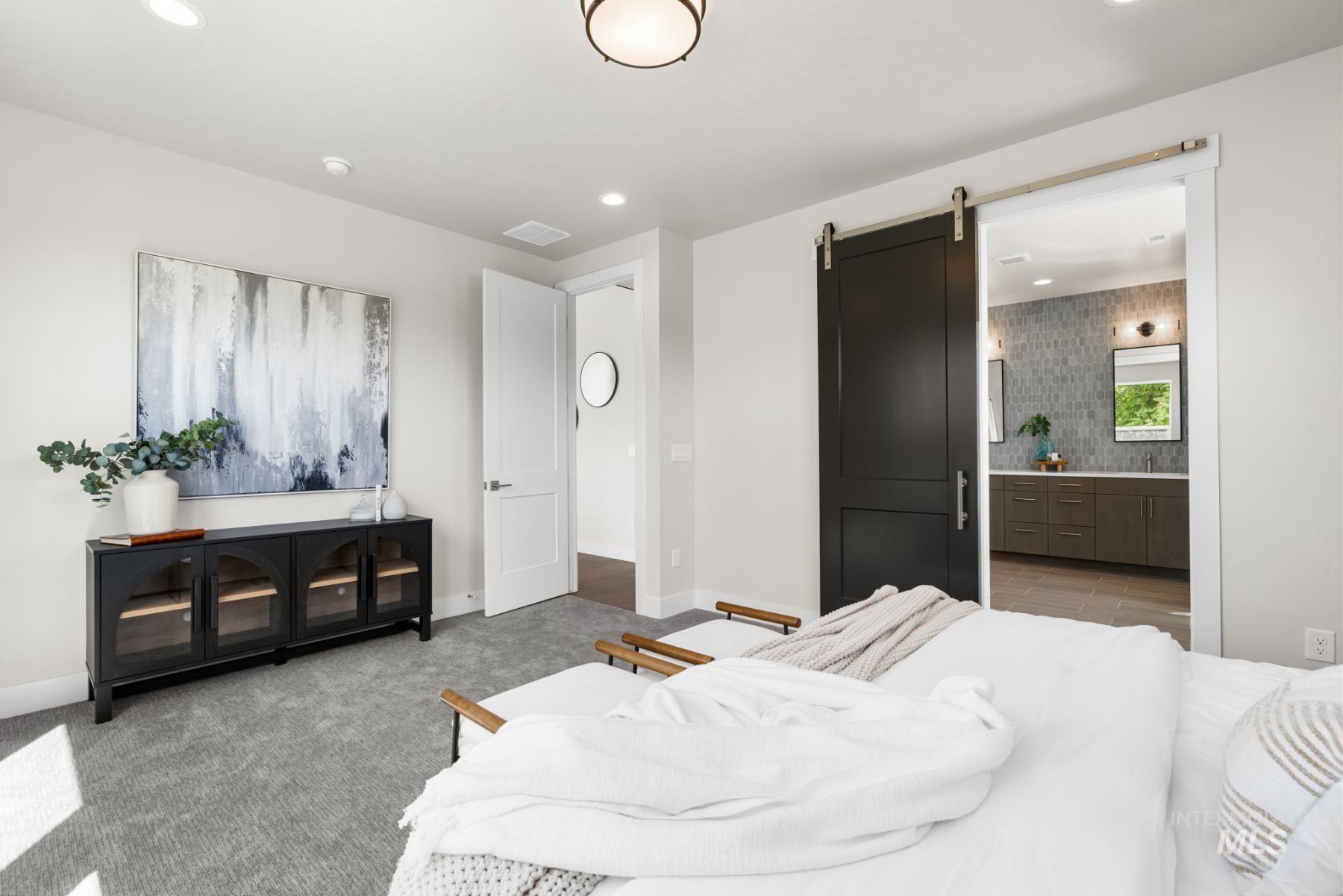 Carpeted bedroom featuring a barn door, recessed lighting, and ensuite bathroom